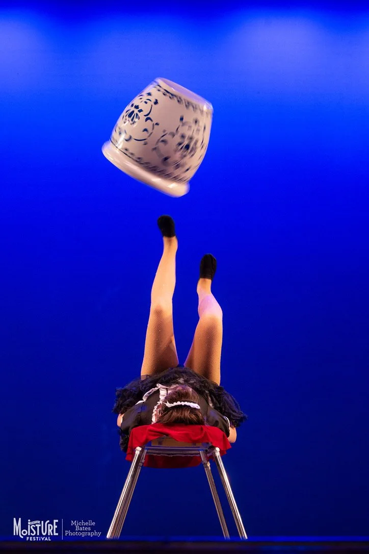 Jack Weinstock foot juggling a jar in front of a blue background at the Moisture Festival.