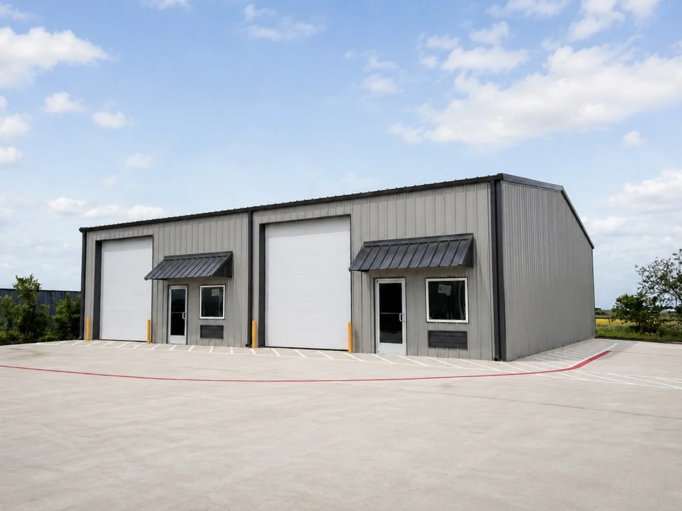 Commercial Space for rent in Ponder, Tx. A large, gray commercial building with two large garage doors, two smaller pedestrian doors, and small windows under black metal awnings, situated on a paved parking lot under a partly cloudy sky.