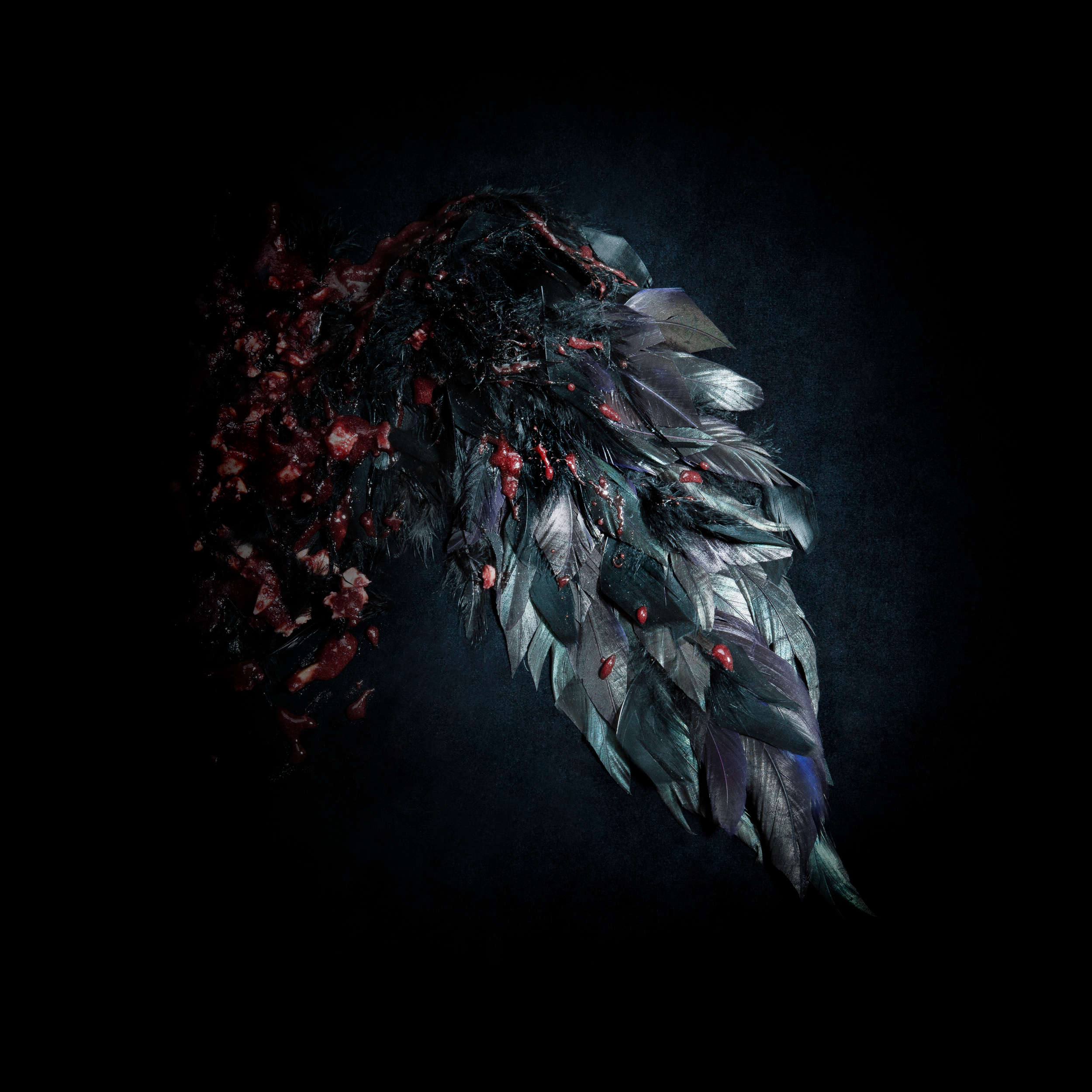 Poupée de style humain avec blessures et organes exposés, portant un costume métallique avec des plumes. Fond sombre