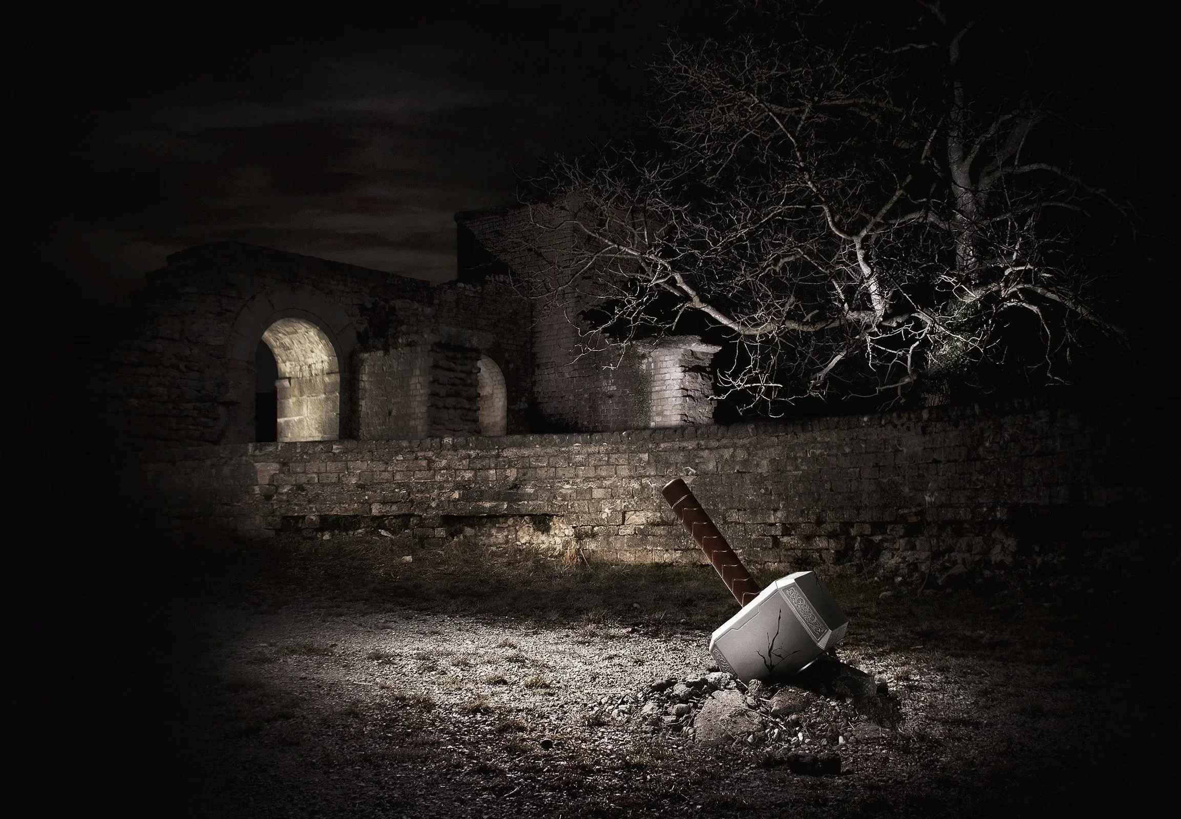 Un arbre sans feuilles, une vieille ruine en pierre et un vieux lampadaire tombé sur le sol lors d'une nuit sombre.