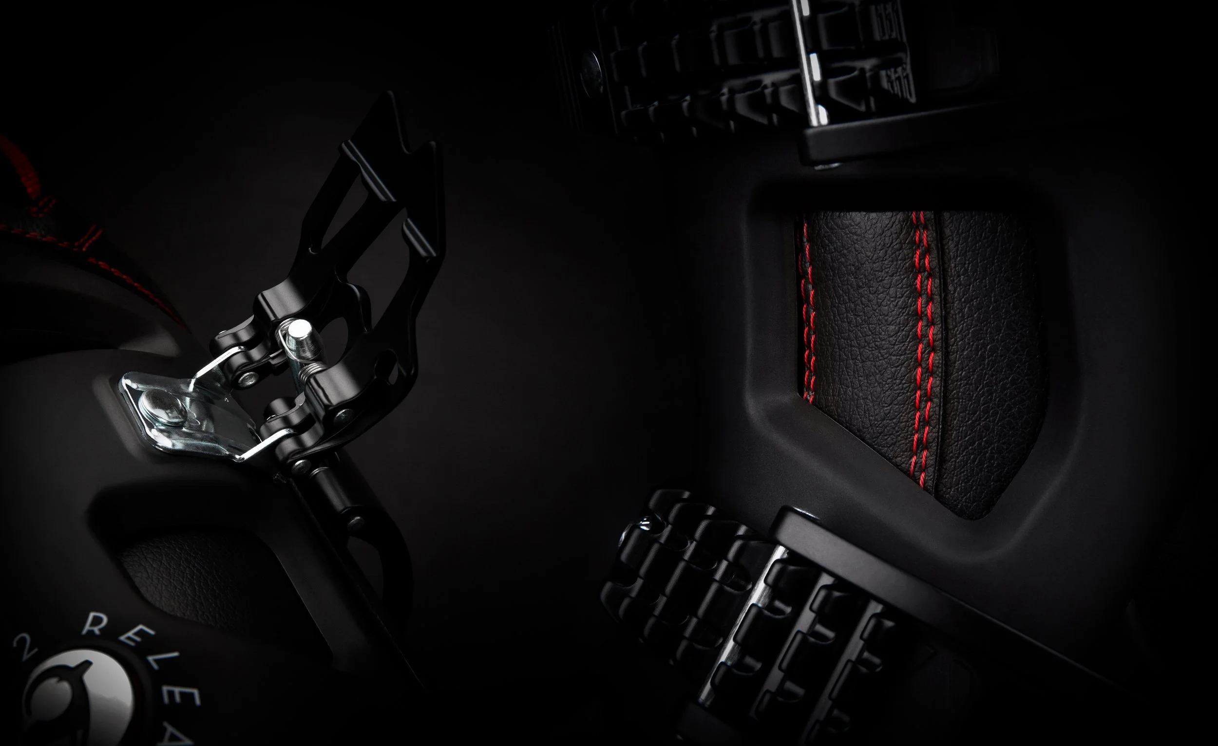 Détail d'une montre avec un bracelet en cuir noir avec des surpiqûres rouges, située à côté d'une pièce métallique et d'un bracelet en métal.
