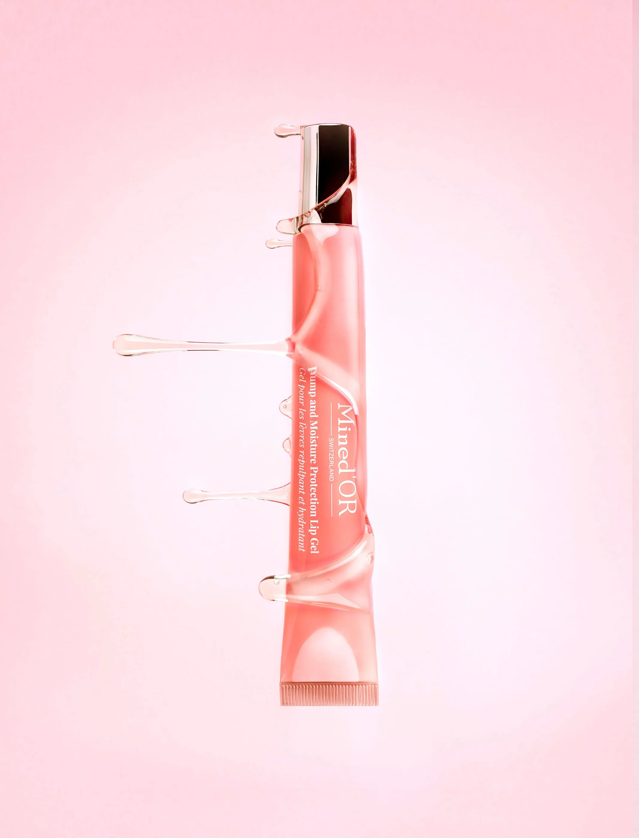 Un tube de gel de protection solaire avec un design rose, posé verticalement, avec des gouttes de gel sur le tube, sur un fond rose.