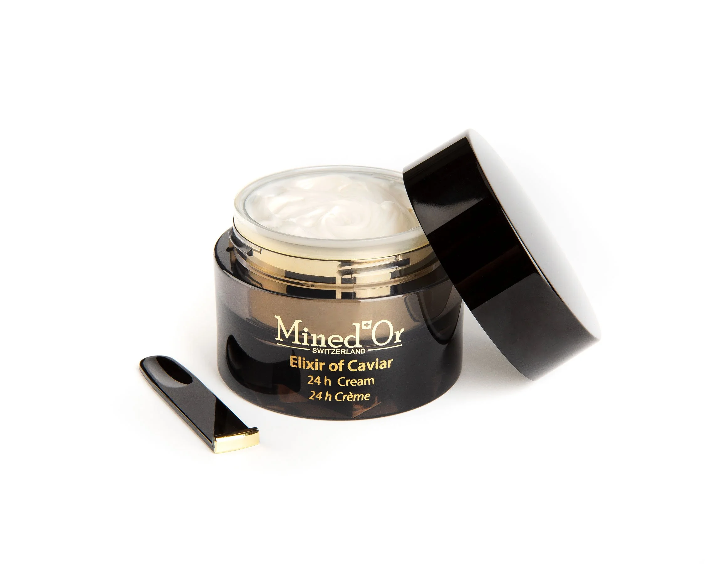 Crème en pot noir avec ornement doré et logo, pot ouvert avec crème blanche, poignée en métal doré, sur fond blanc.