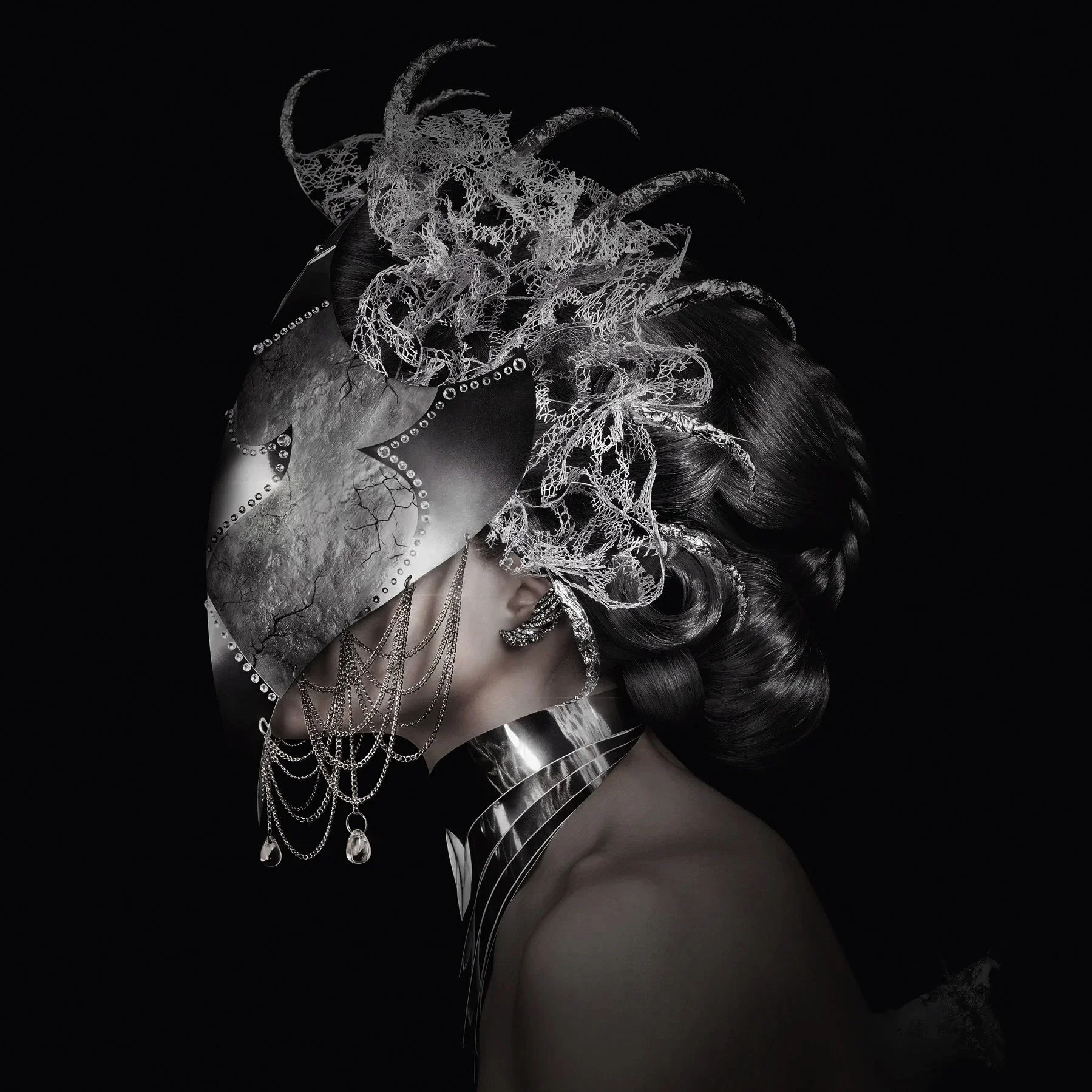 Une femme porte un masque en miroir, des bijoux en argent, et une coiffe élaborée avec des feuilles dorées et des cornes d'animal stylisées dans une image en noir et blanc.