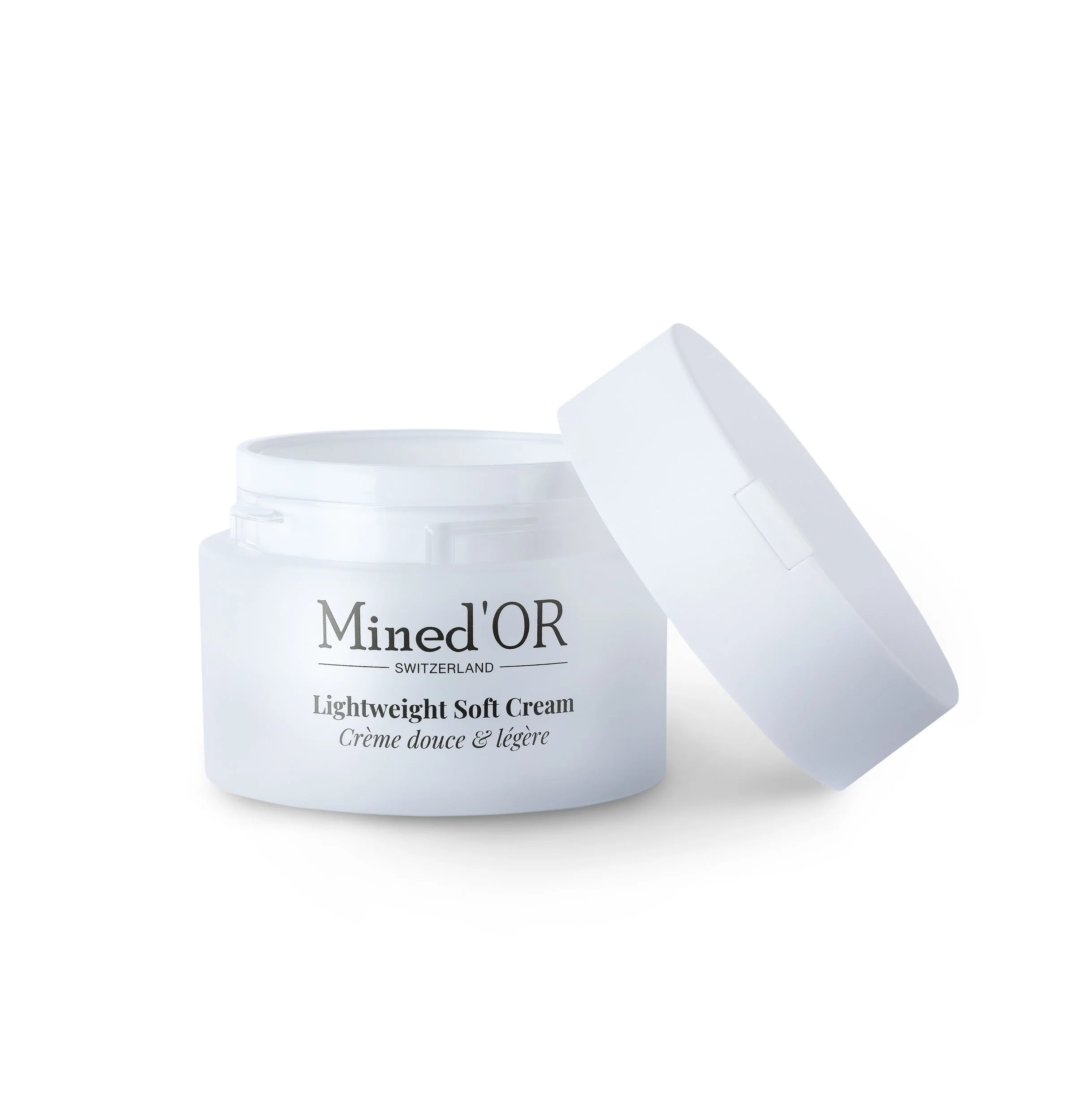 Pot de crème Mined'OR Switzerland blanc avec son couvercle légèrement ouvert, indiquant une crème douce et légère.