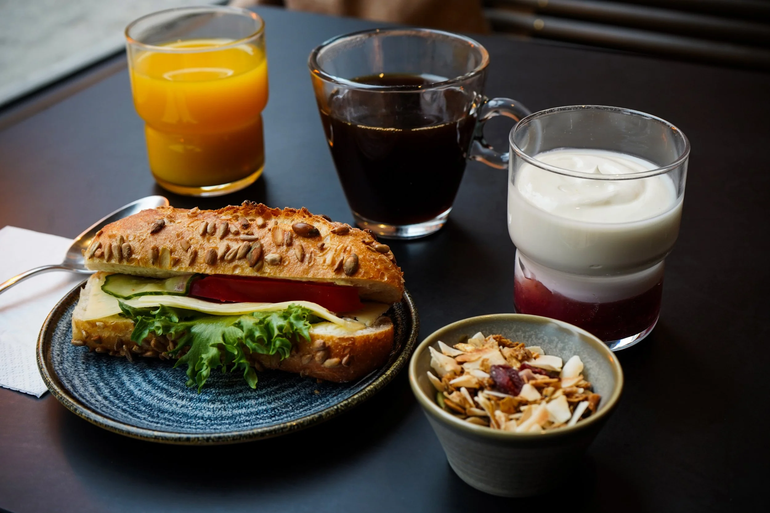 Frukost med smörgås, tre glas juice, kaffe och yoghurt med sylt.