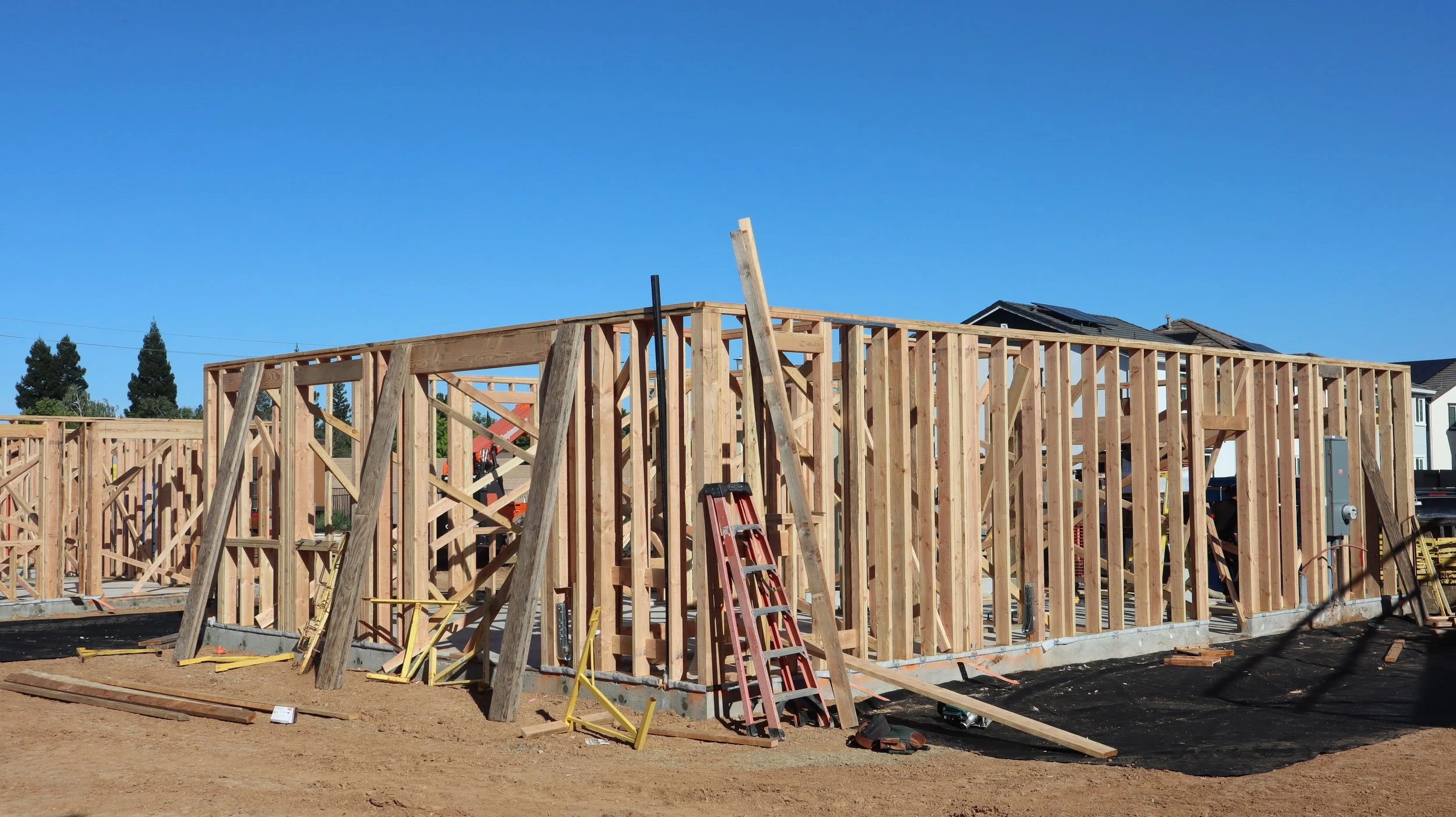 Wood framing for a building under construction on a clear day with blue sky.