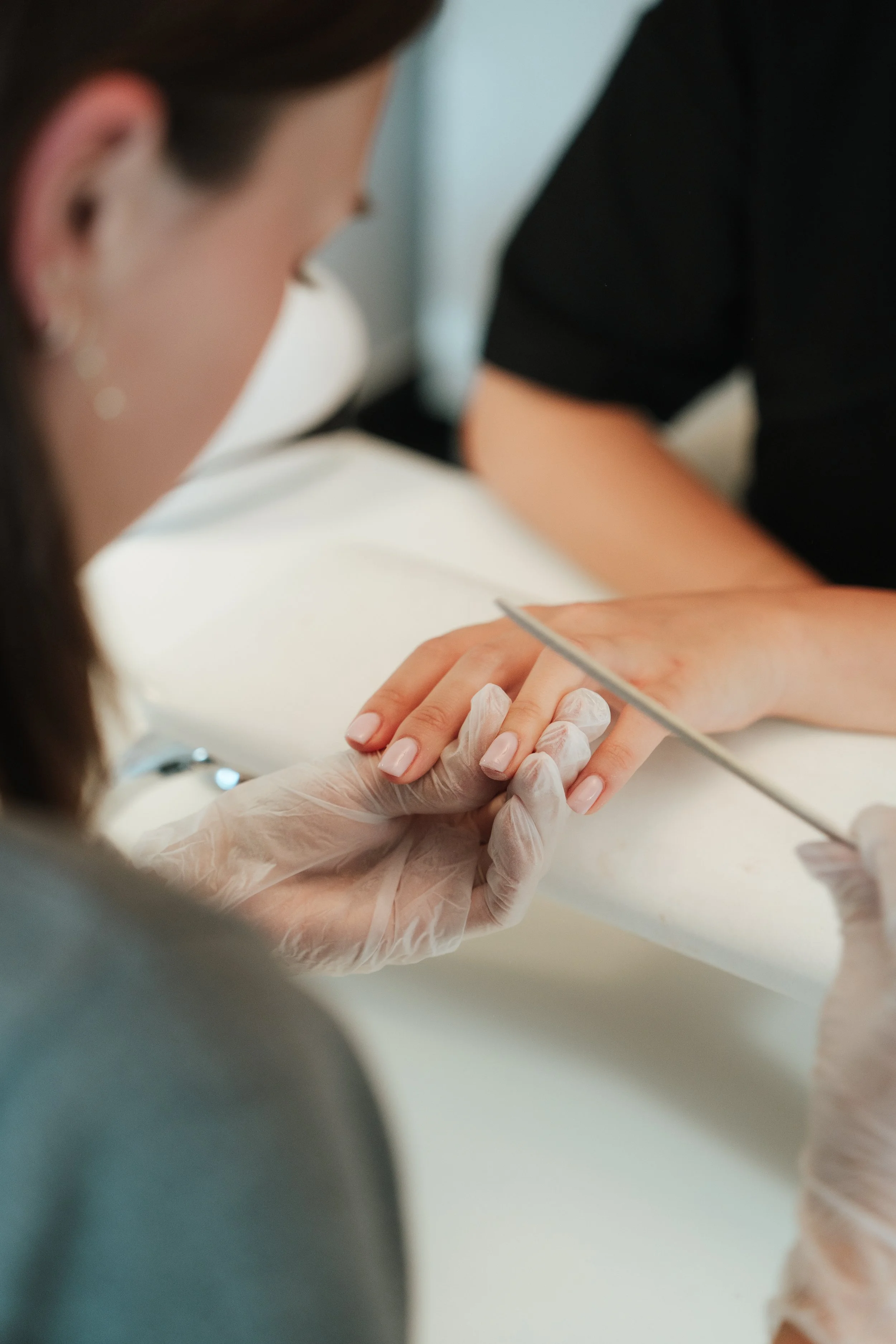 Close-up of a woman getting a manicure at a salon, with a technician applying nail polish.