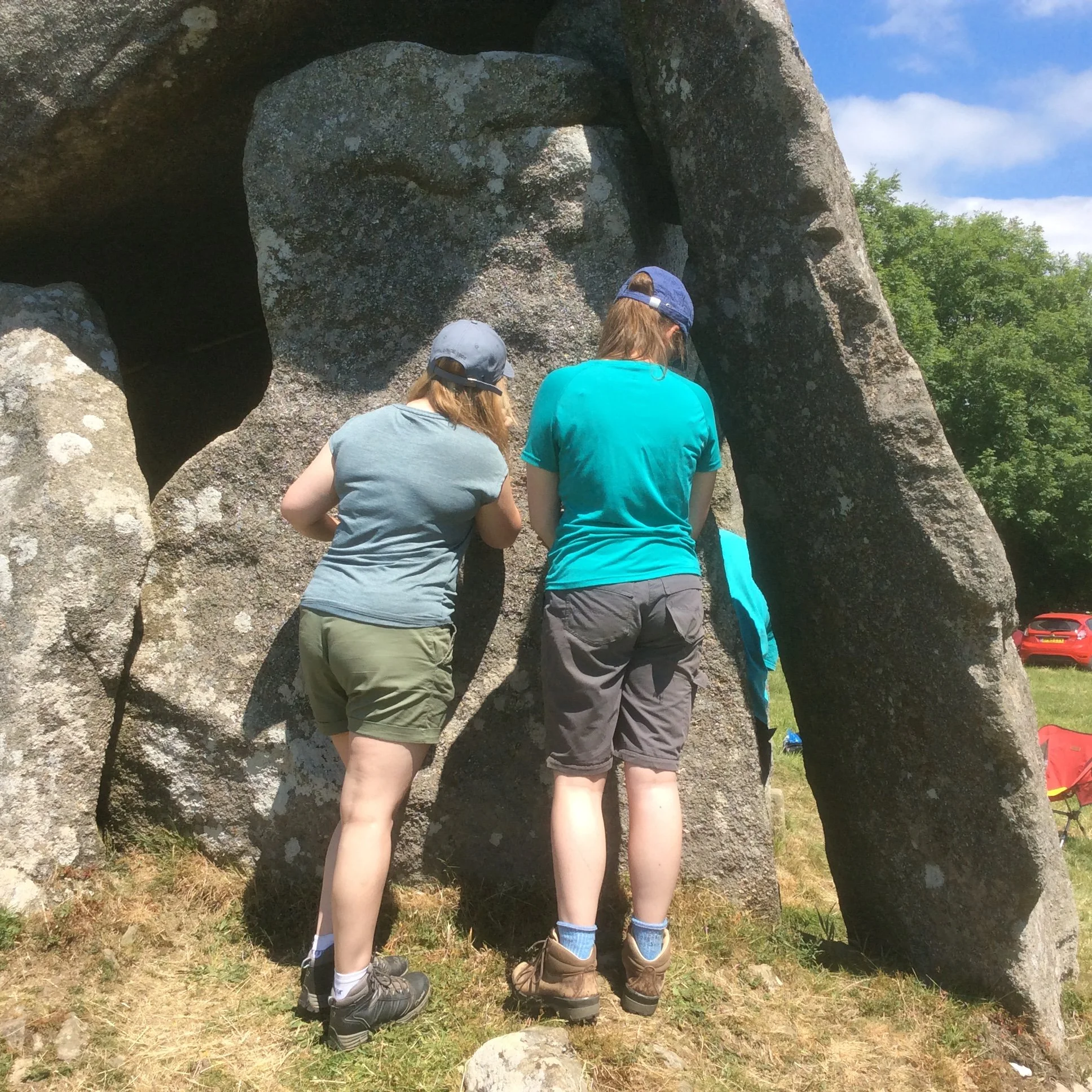 Two geology students being taught how to study the rocks of Trethevy Quoit to help archaeologists understand the site.