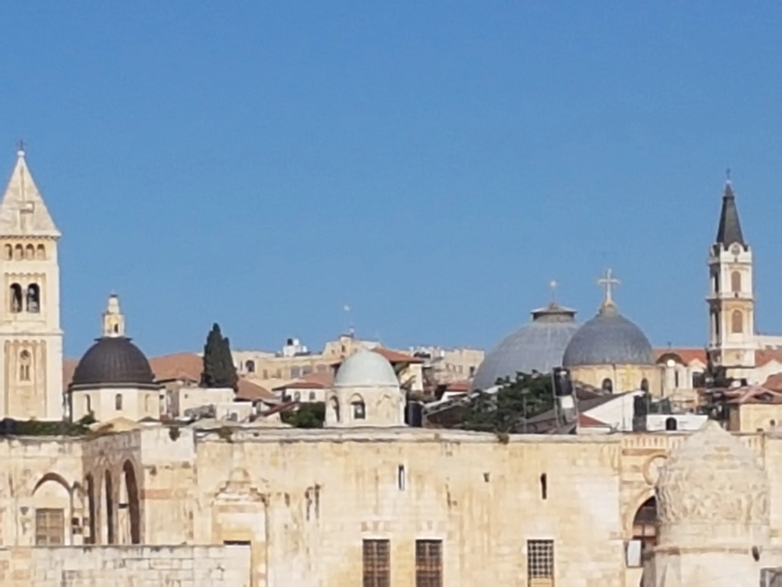 Cityscape with historic church buildings, including tall towers and domed roofs, under a clear blue sky.