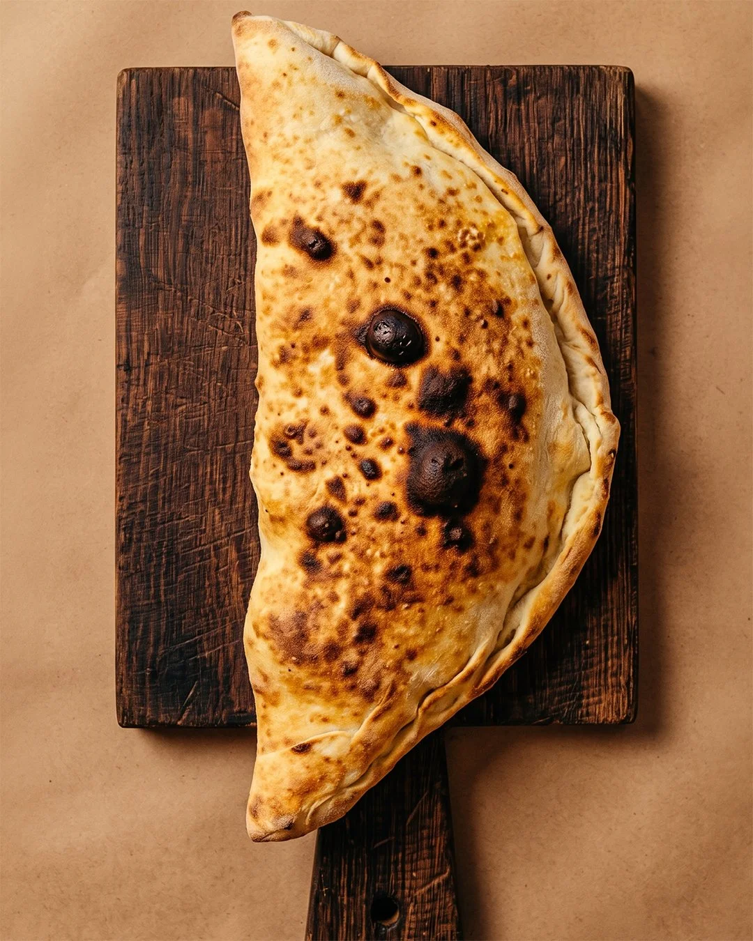 Calzone doré sorti du four, servi avec une salade de roquette et tomates cerises