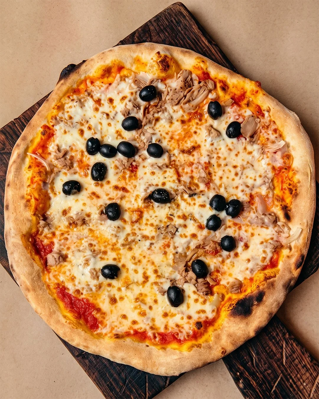 Pizza garnie de fromage, olives noires et poulet, pizzeria Bellucci à Yverdon-les-Bains