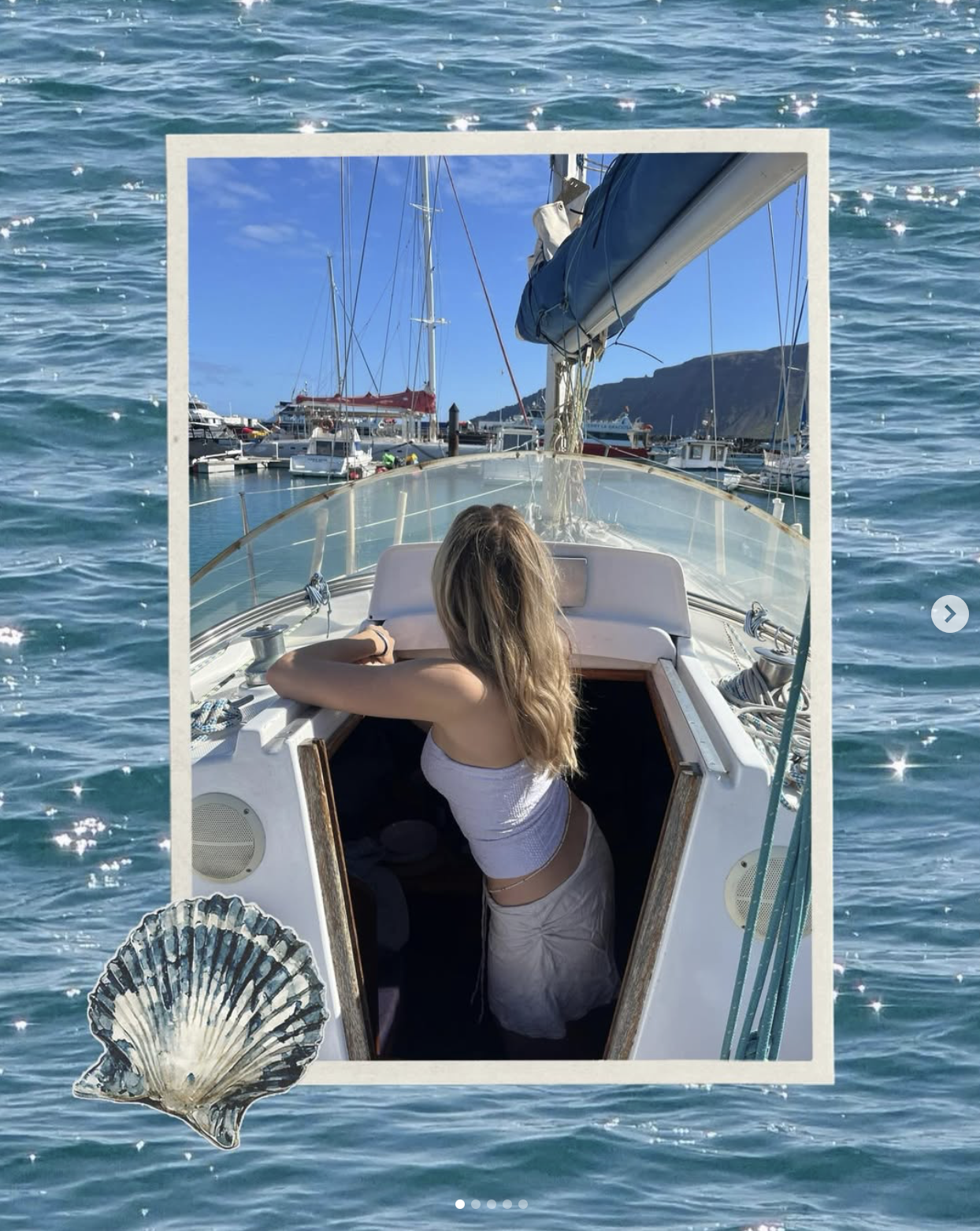 A woman with long blonde hair sits on a boat, facing away, with a marina and blue sky in the background. The photo is edited with a frame and seashell graphics around the edges, giving it a scrapbook style.