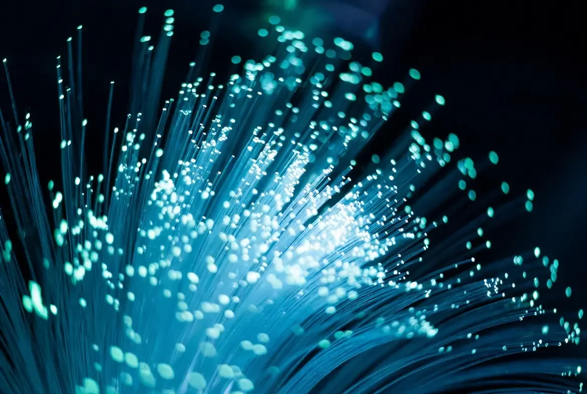 Close-up of fiber optic cables with glowing blue light and sparkling points of light