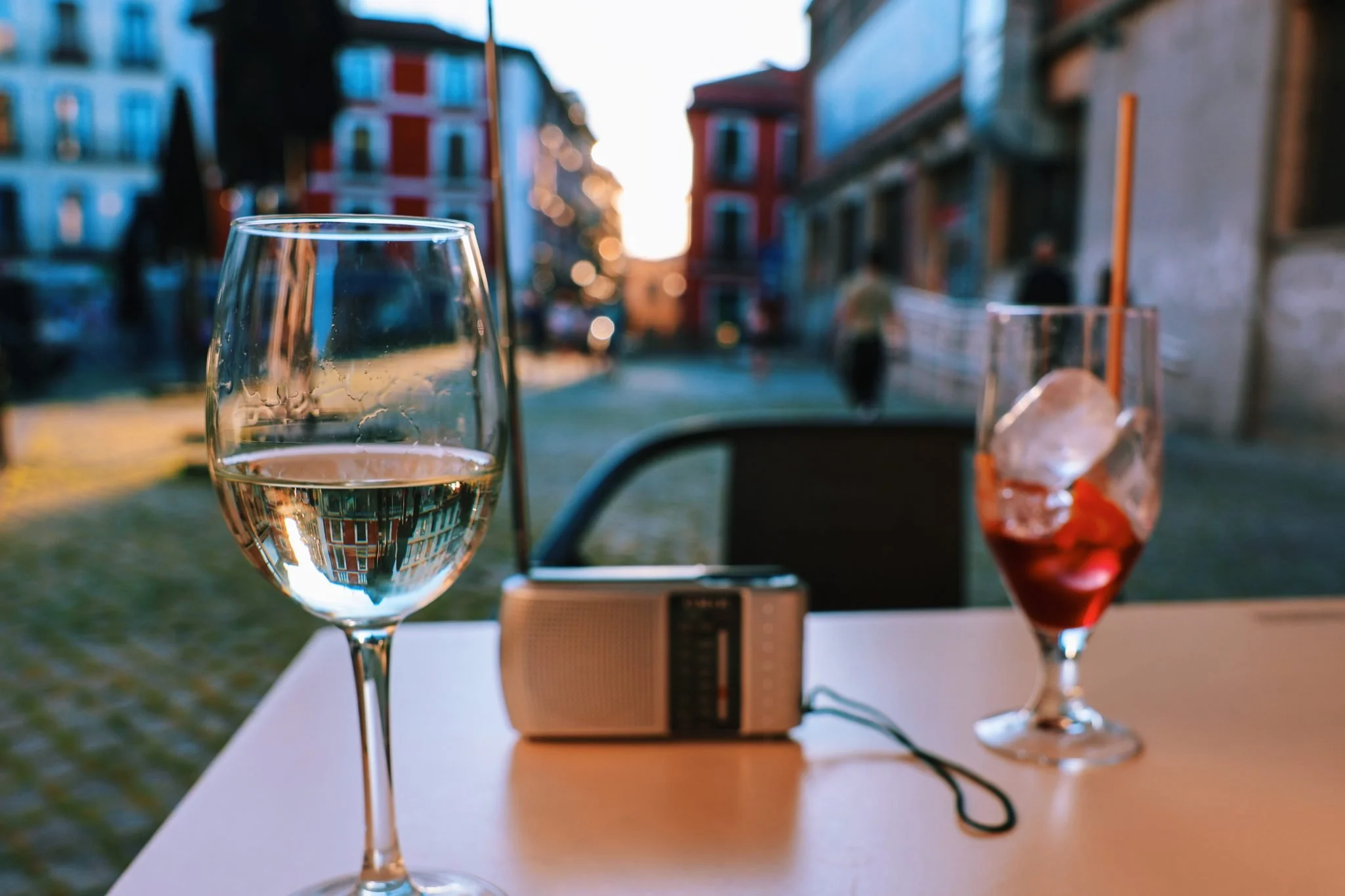 a terrace in spain at twilight with two glasses of wine and a battery-powered radio