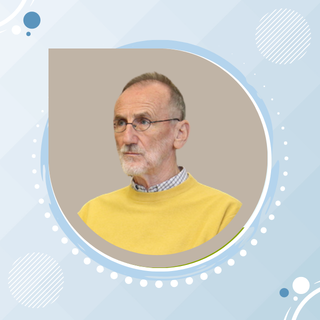 A portrait of an elderly man with glasses and gray hair, wearing a yellow sweater over a collared shirt, against a plain background.