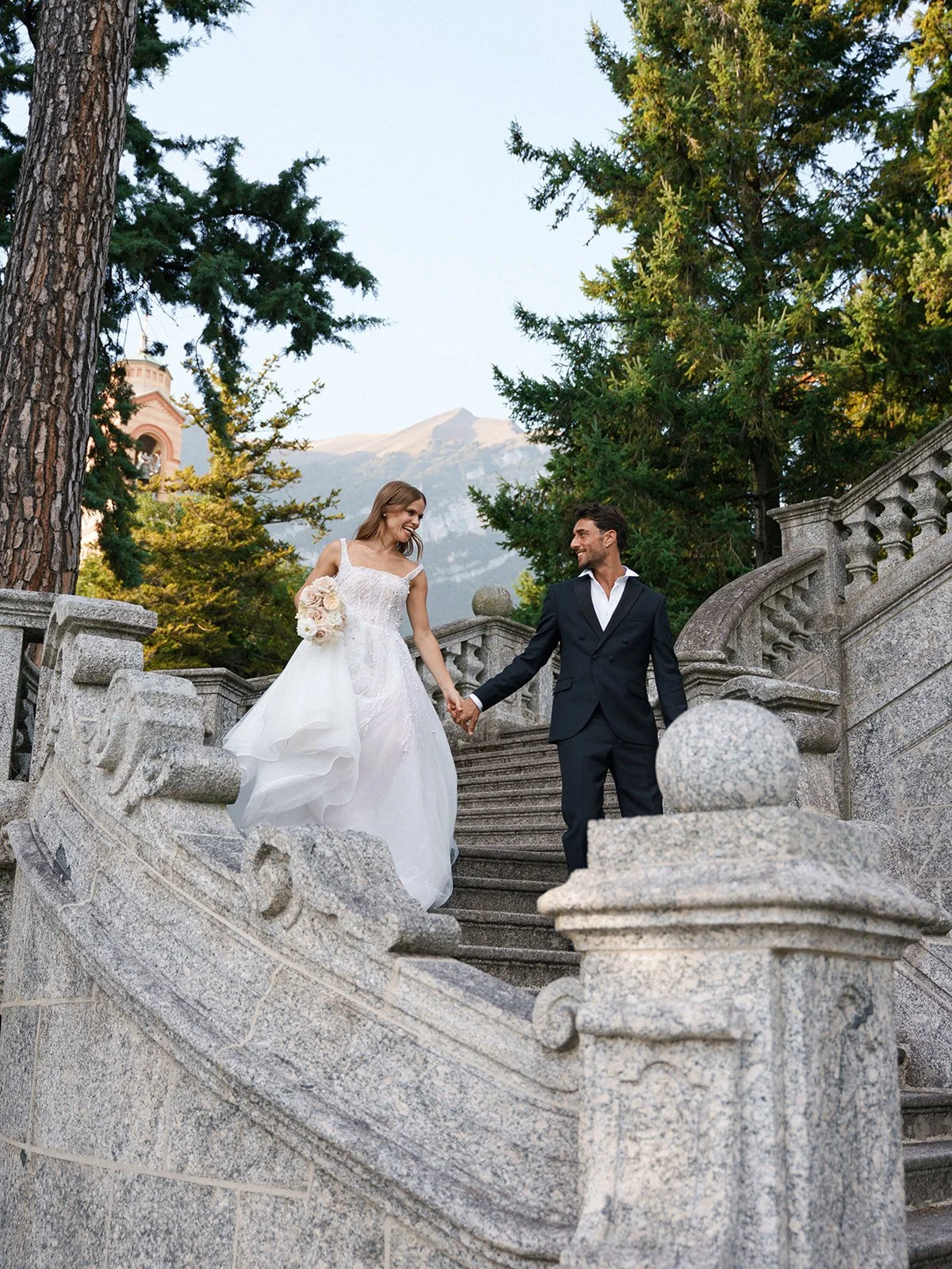 Couple descending an ornate stone staircase during a private garden elopement on Lake Como.