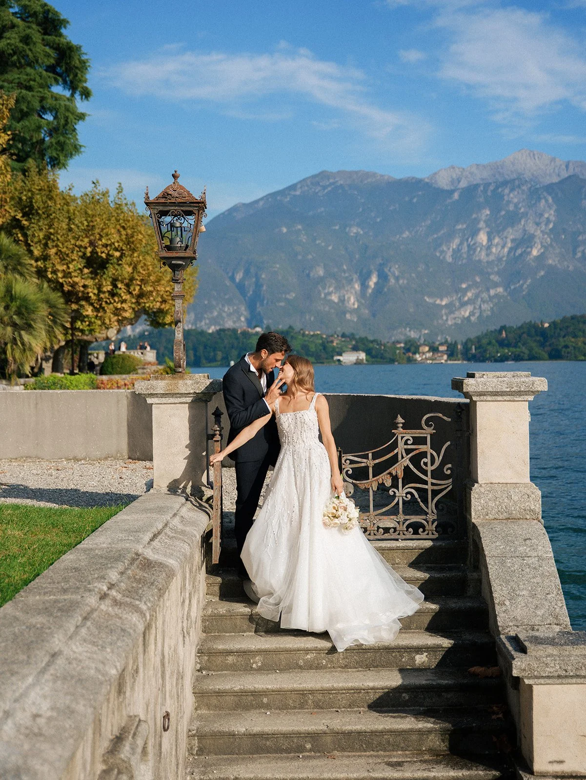 Couple embracing on historic stone steps beside Lake Como during an intimate garden elopement.