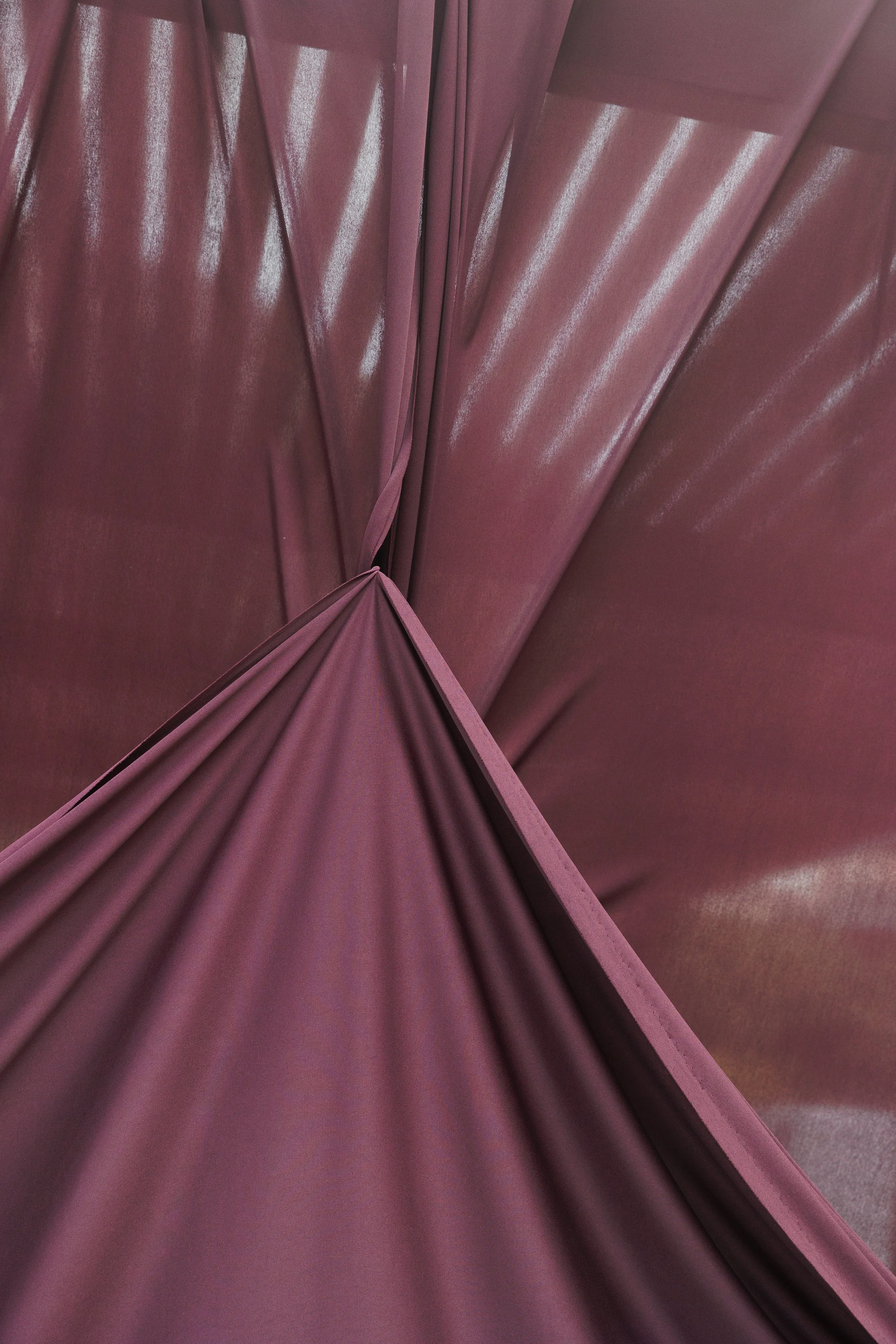 Close-up of layered aubergine fabric draping used for a contemporary wedding ceremony backdrop.