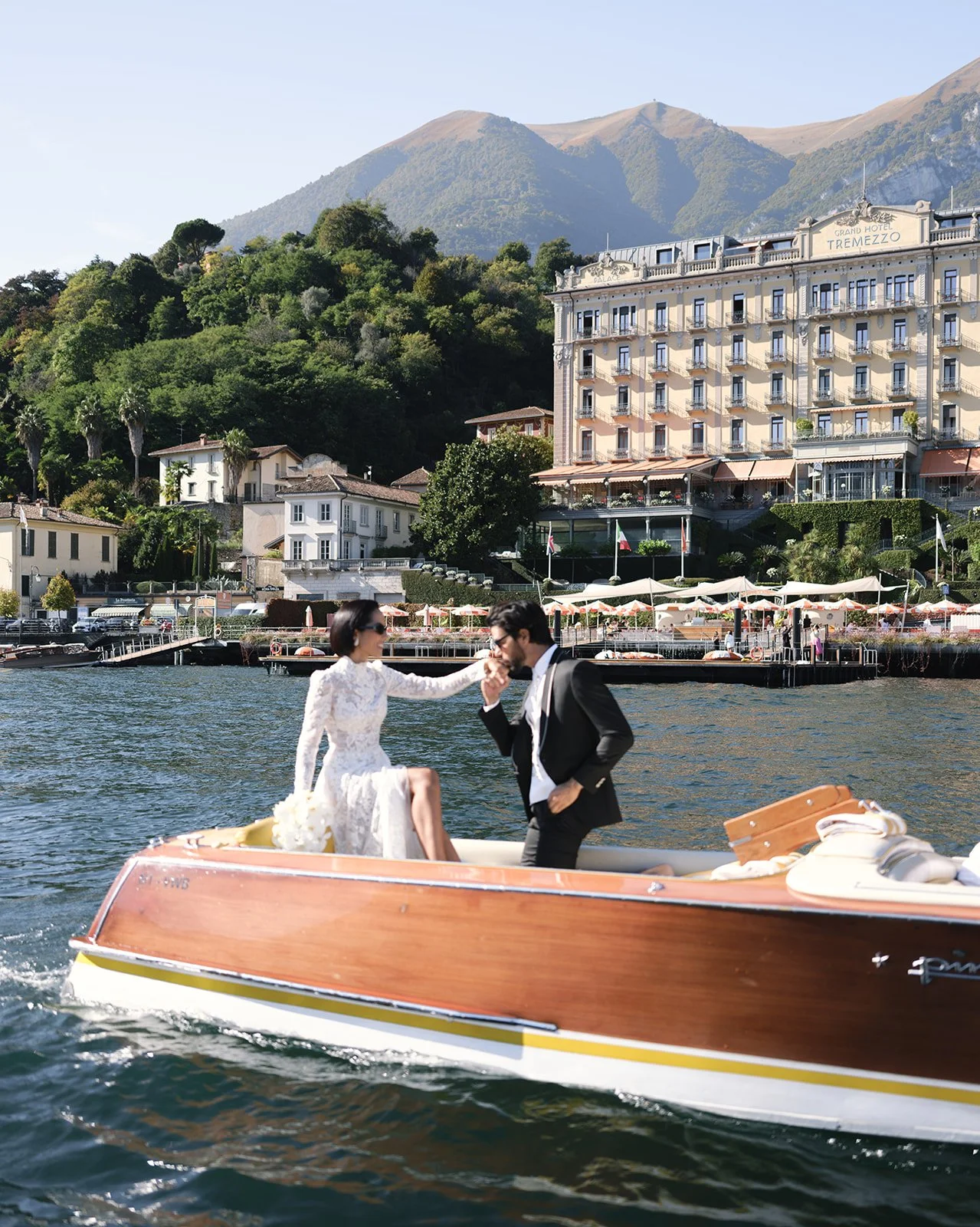Bride and groom arriving by vintage boat in front of Grand Hotel Tremezzo on Lake Como.