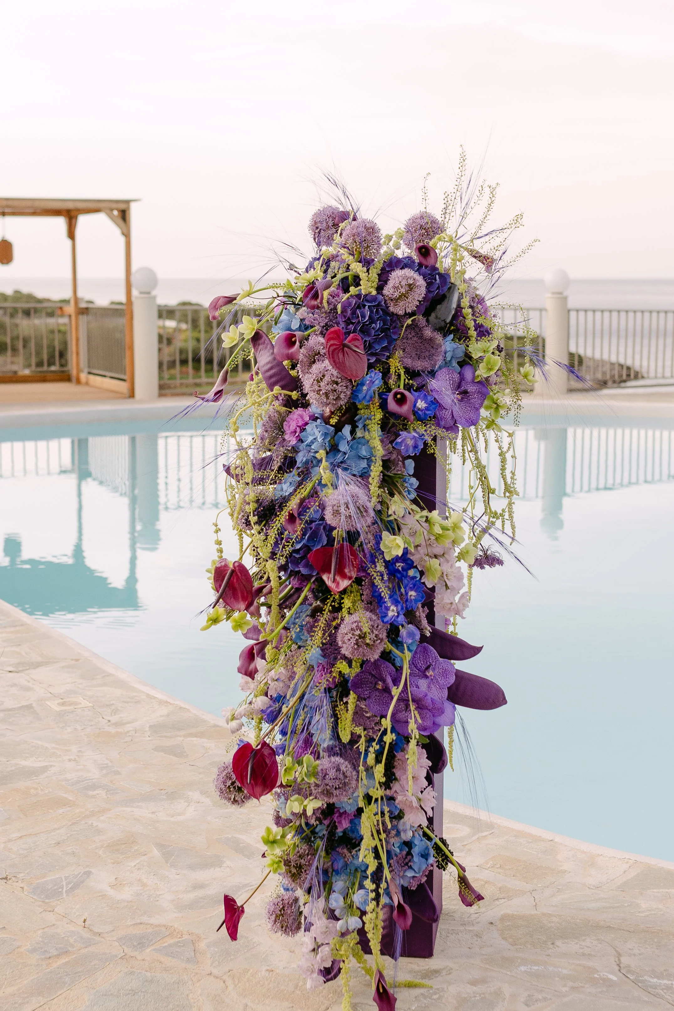 Statement floral installation in saturated violet, cobalt and pink beside a swimming pool in Crete.