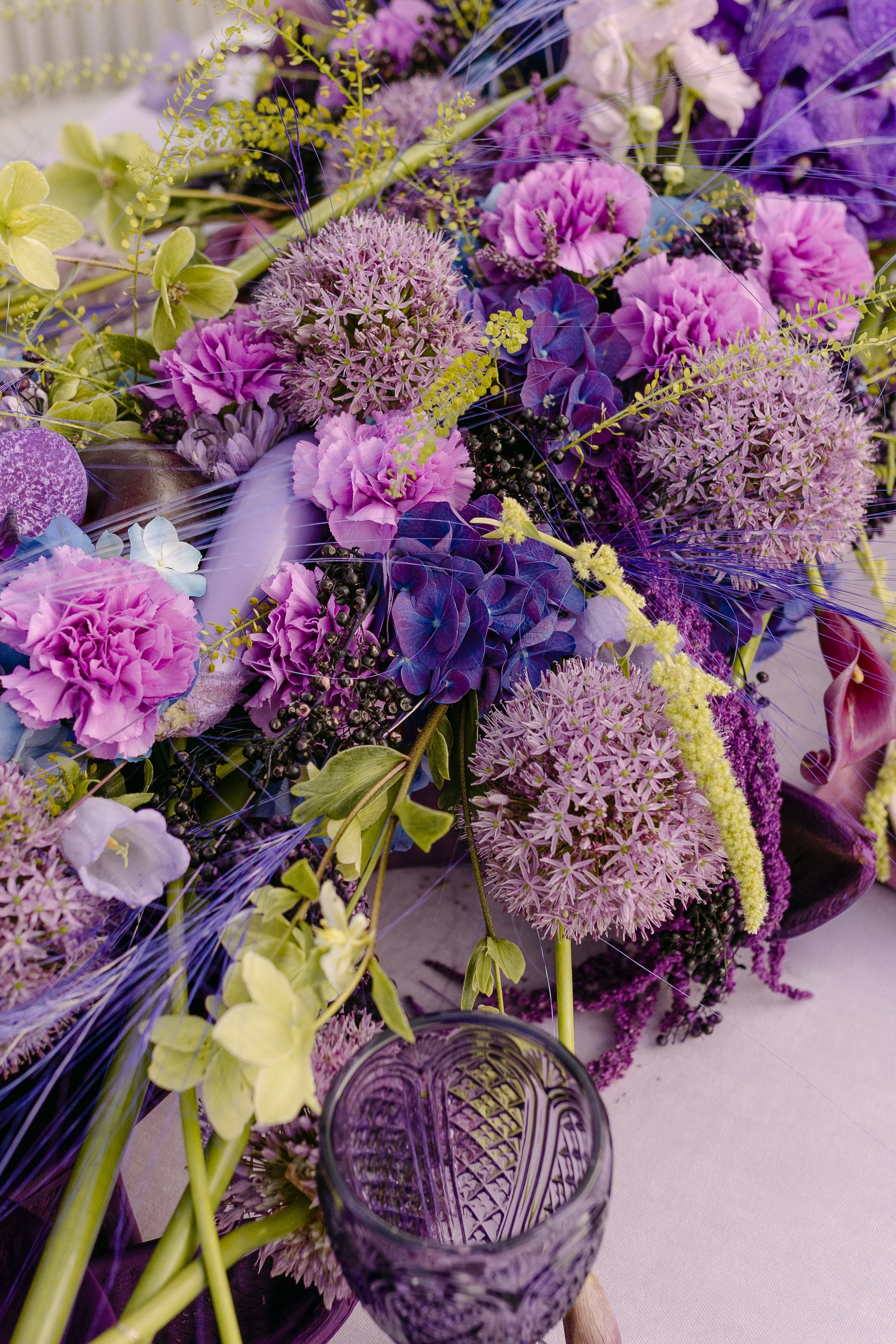 Richly layered wedding flowers in violet, magenta, cobalt and soft green tones.