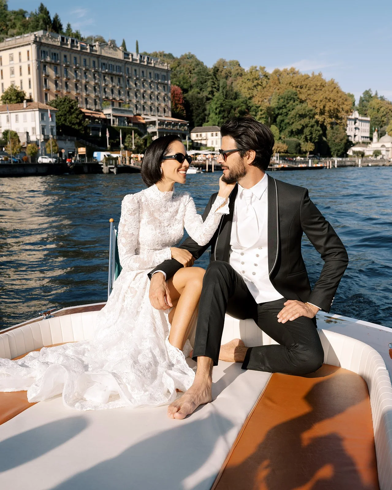 Bride and groom seated on a vintage wooden boat during a Lake Como wedding celebration.