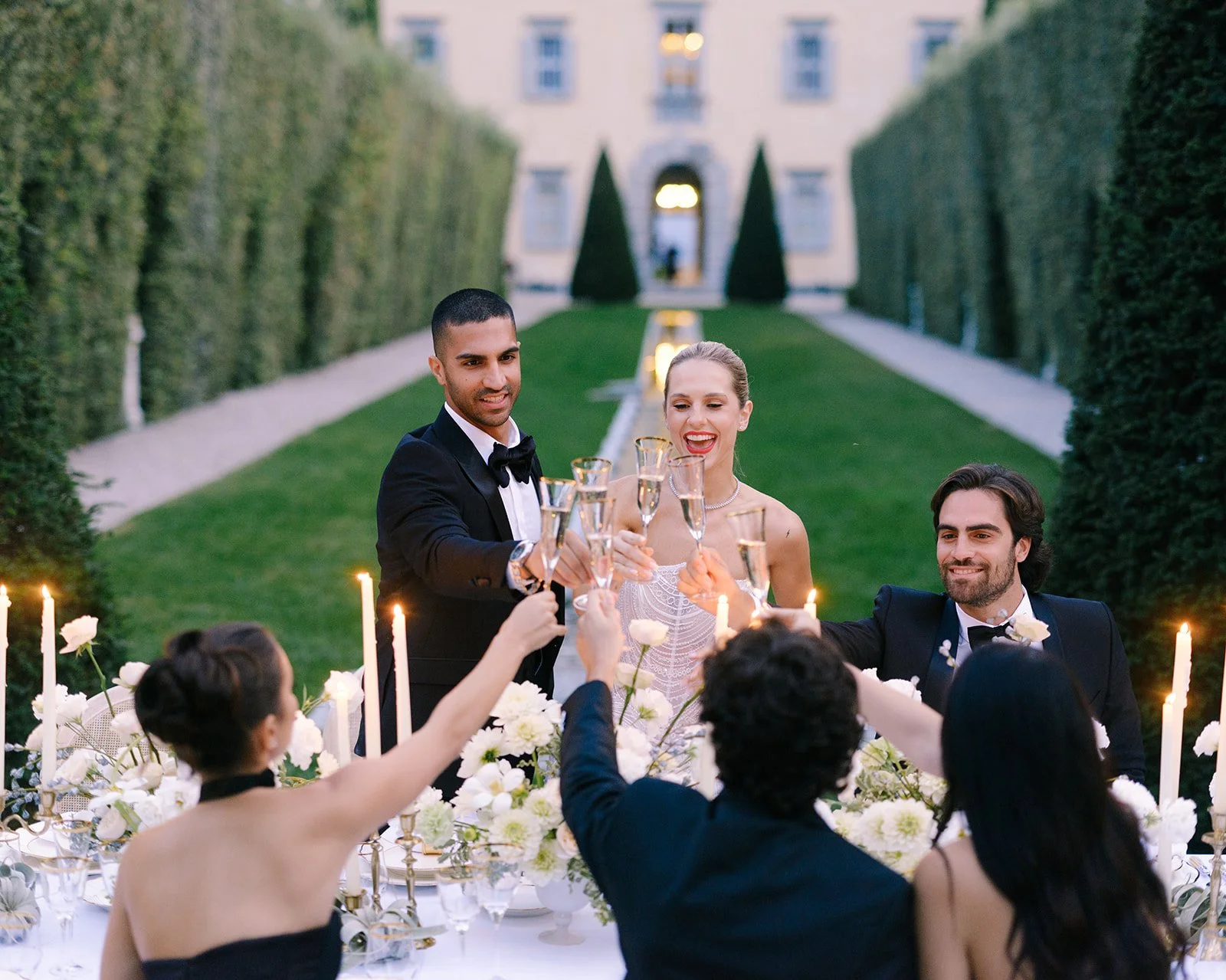 Bride, groom and guests raising champagne glasses during a wedding dinner at Villa Balbiano.