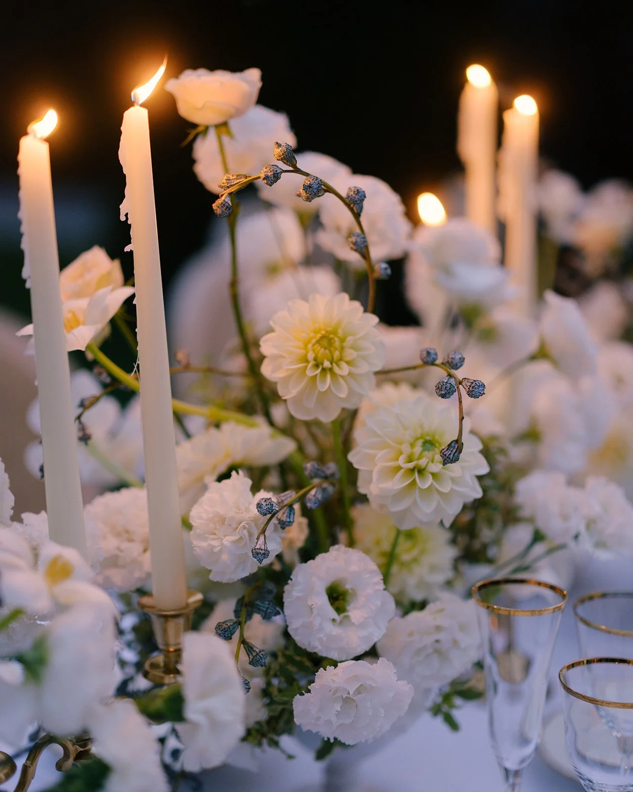 White floral arrangements and taper candles during an evening wedding dinner at Villa Balbiano.