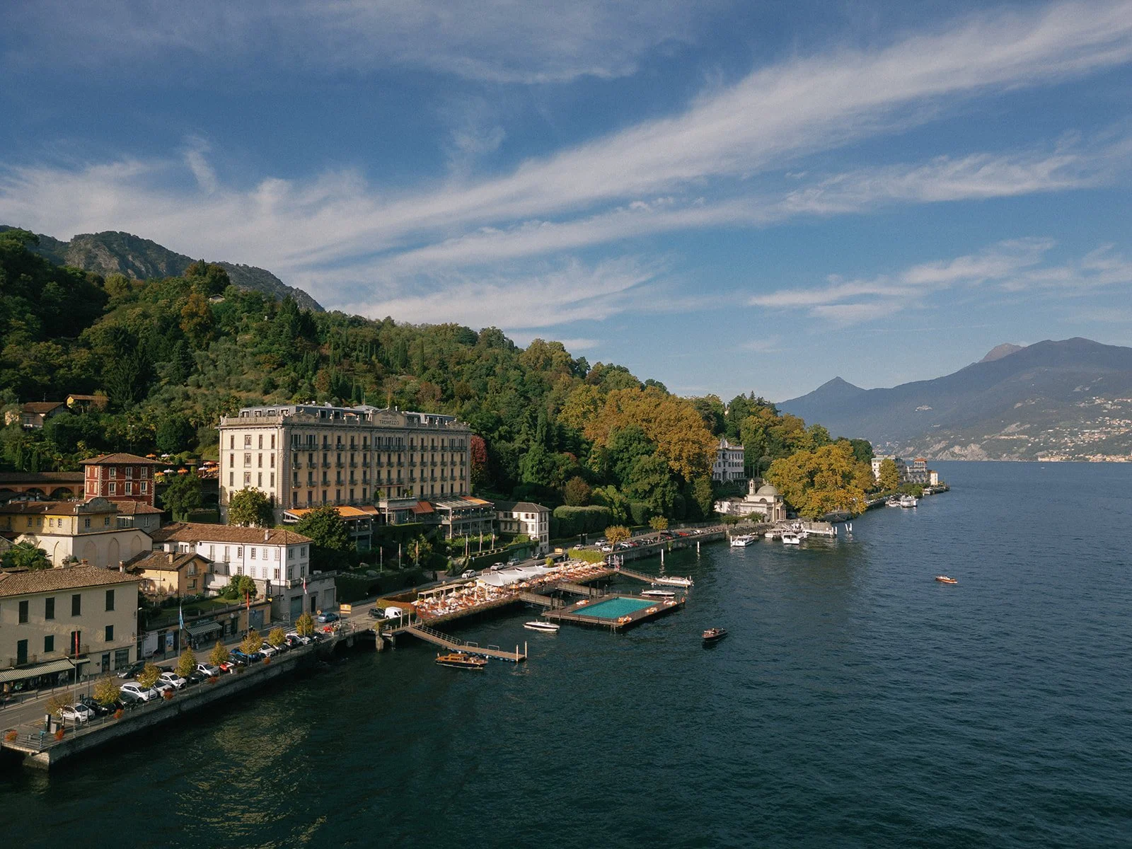 Aerial view of Grand Hotel Tremezzo on the shores of Lake Como, surrounded by mountains and waterfront terraces.