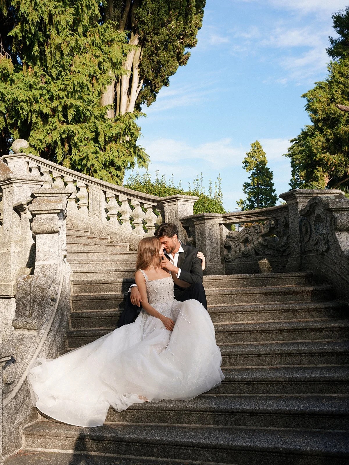 Couple seated closely together on an ornate stone staircase during an intimate elopement on Lake Como.