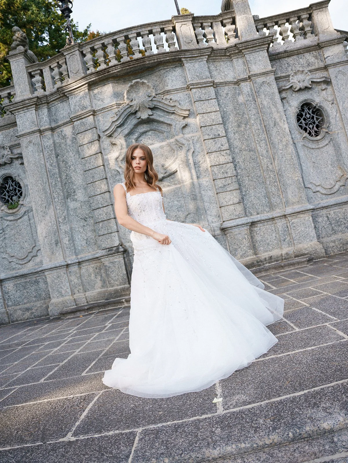 Bride in a full wedding gown standing in front of ornate stone architecture during a Lake Como garden elopement.