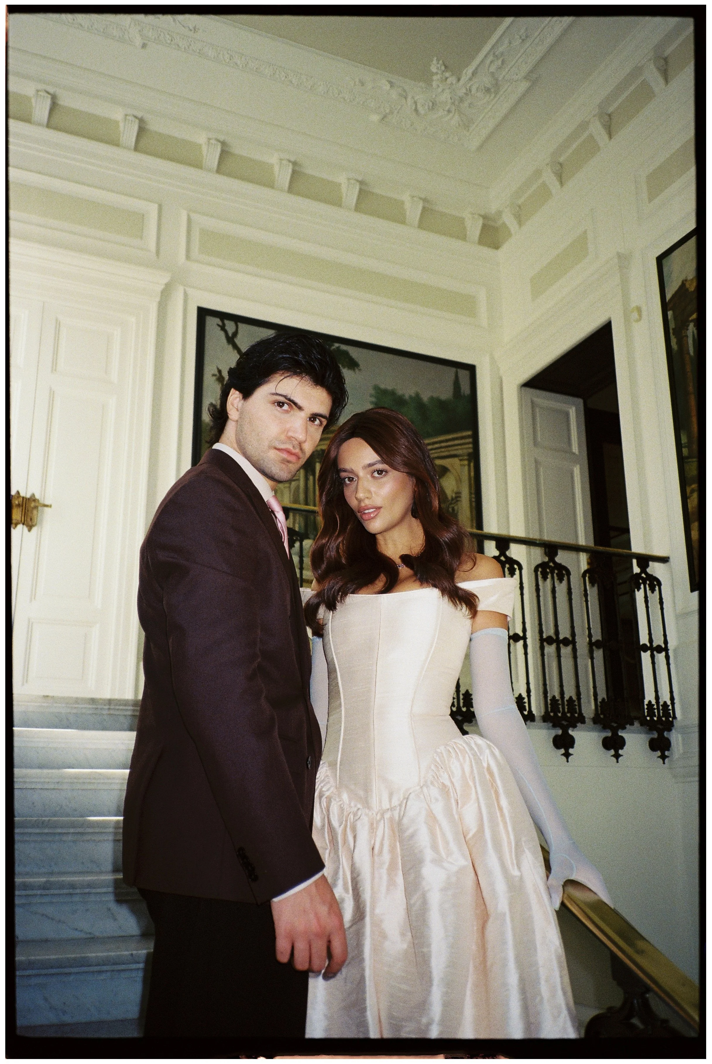 Bride and groom beside a staircase in an ornate white interior at Villa Astor in Sorrento, Italy.