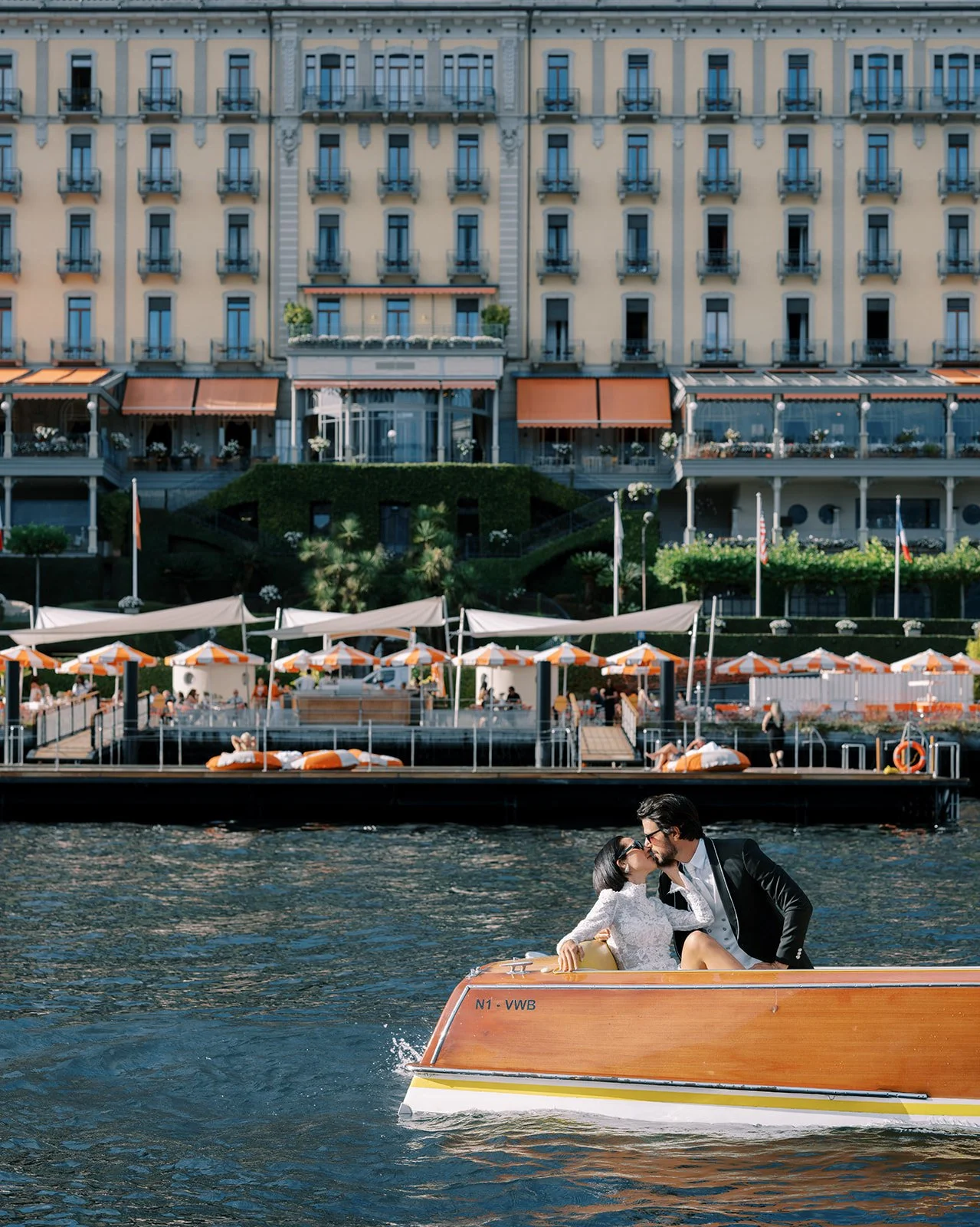 Bride and groom arriving by vintage boat in front of Grand Hotel Tremezzo on Lake Como.