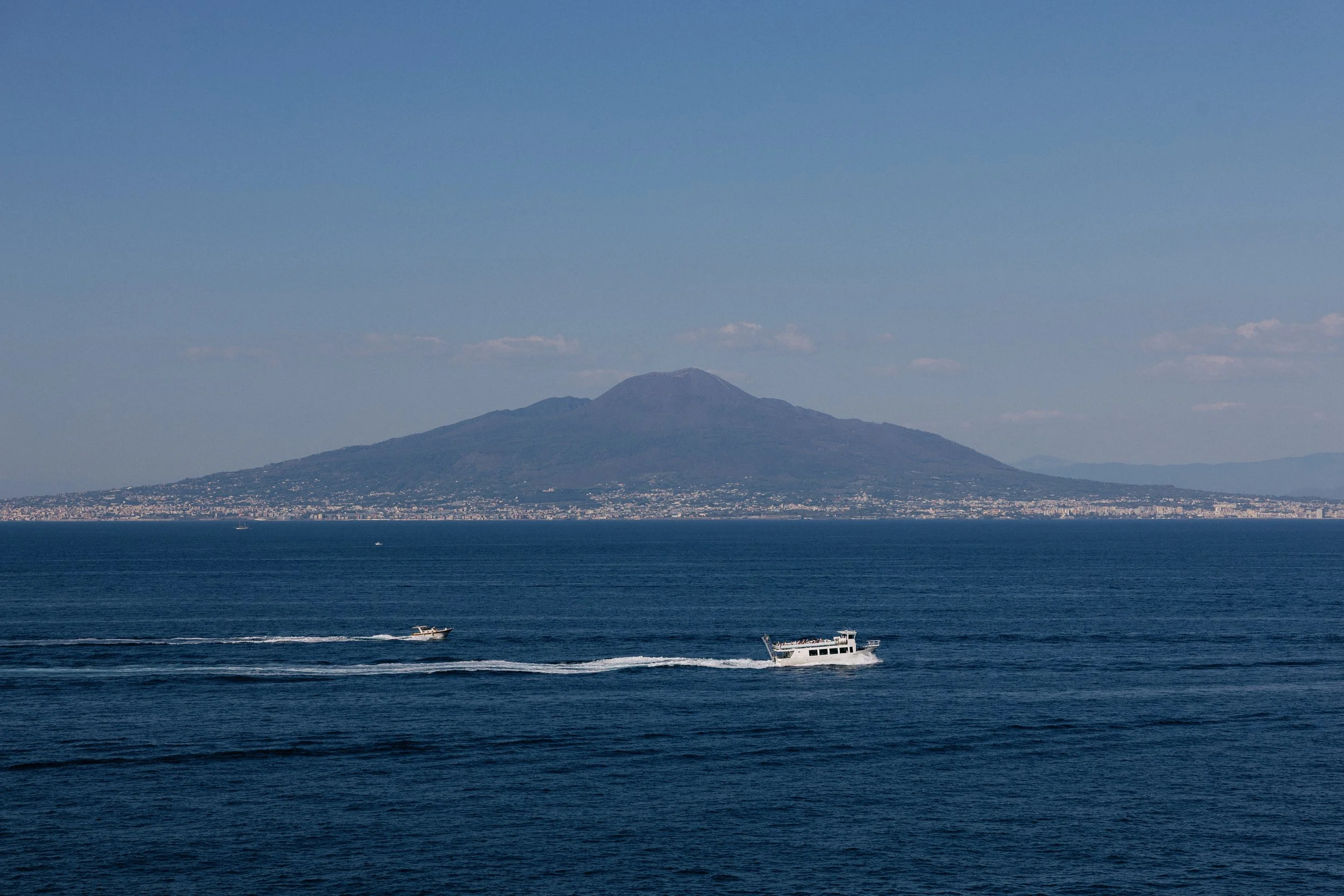 boat crossing the Bay of Naples with Mount Vesuvius and the coastline in the distance.