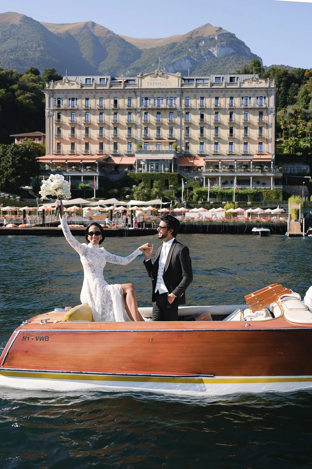 Bride and groom arriving by vintage boat in front of Grand Hotel Tremezzo on Lake Como.