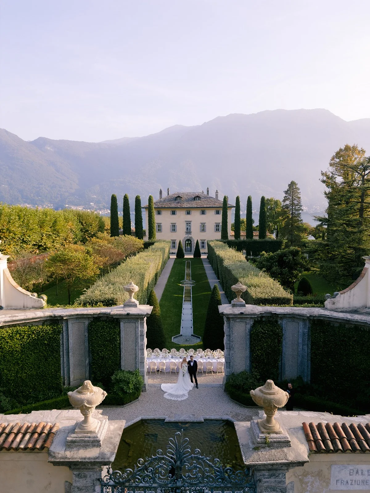 drone shot of villa balbiano showing the green path leading to the villa with the tablescape and bride and groom in the frame
