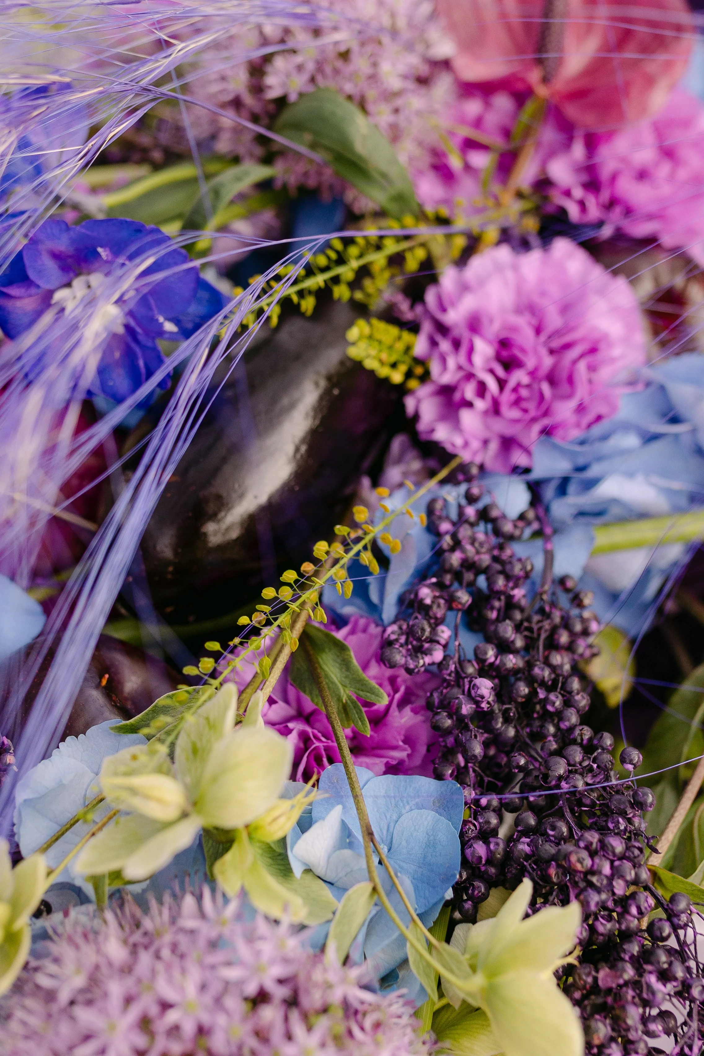 Dramatic floral detail with dark sculptural elements, cobalt hydrangeas and vivid purple flowers.