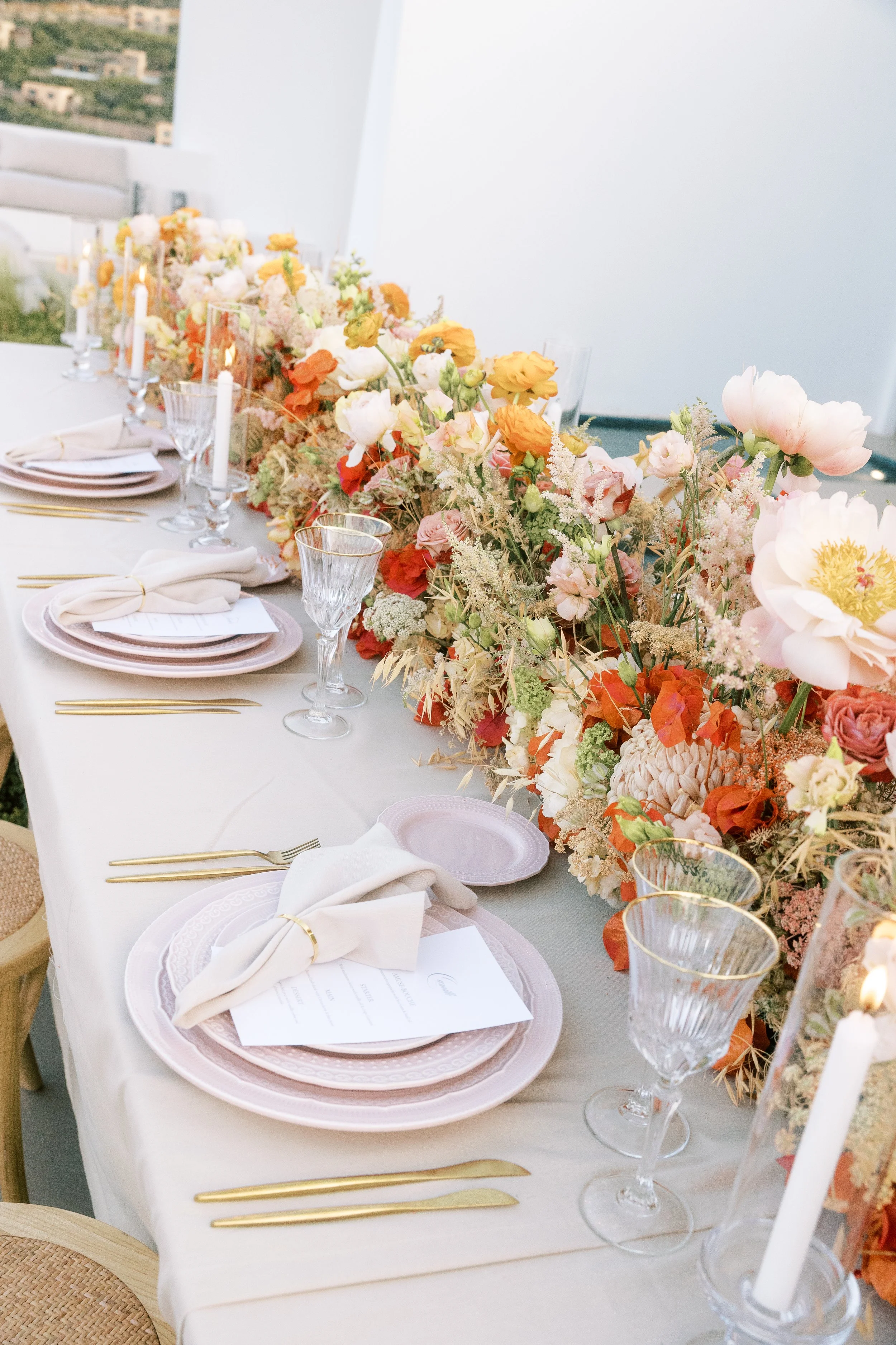 Wedding table with pink plates, peach and orange flowers and candlelight