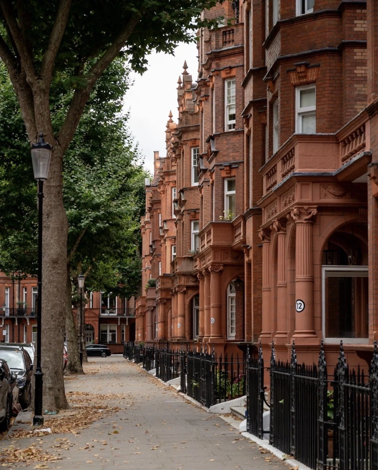 Street view of red brick Victorian - style residential properties in Sloane Square, Chelsea, a development opportunity with decorative architectural details and small balconies.