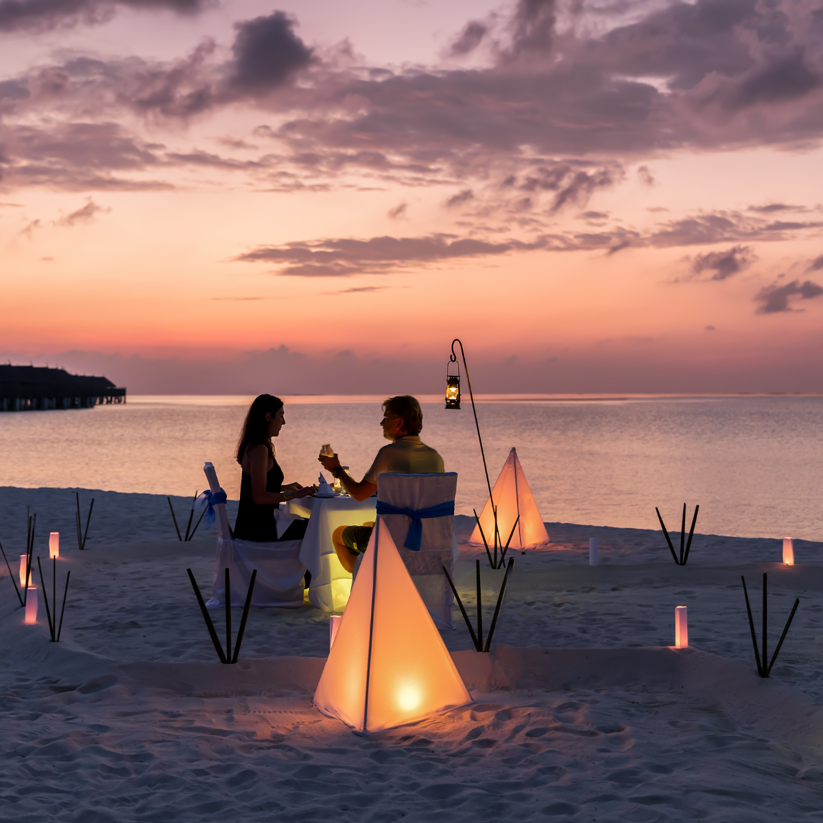a couple having dinner on a beach in Greece at sunset celebrating their anniversary
