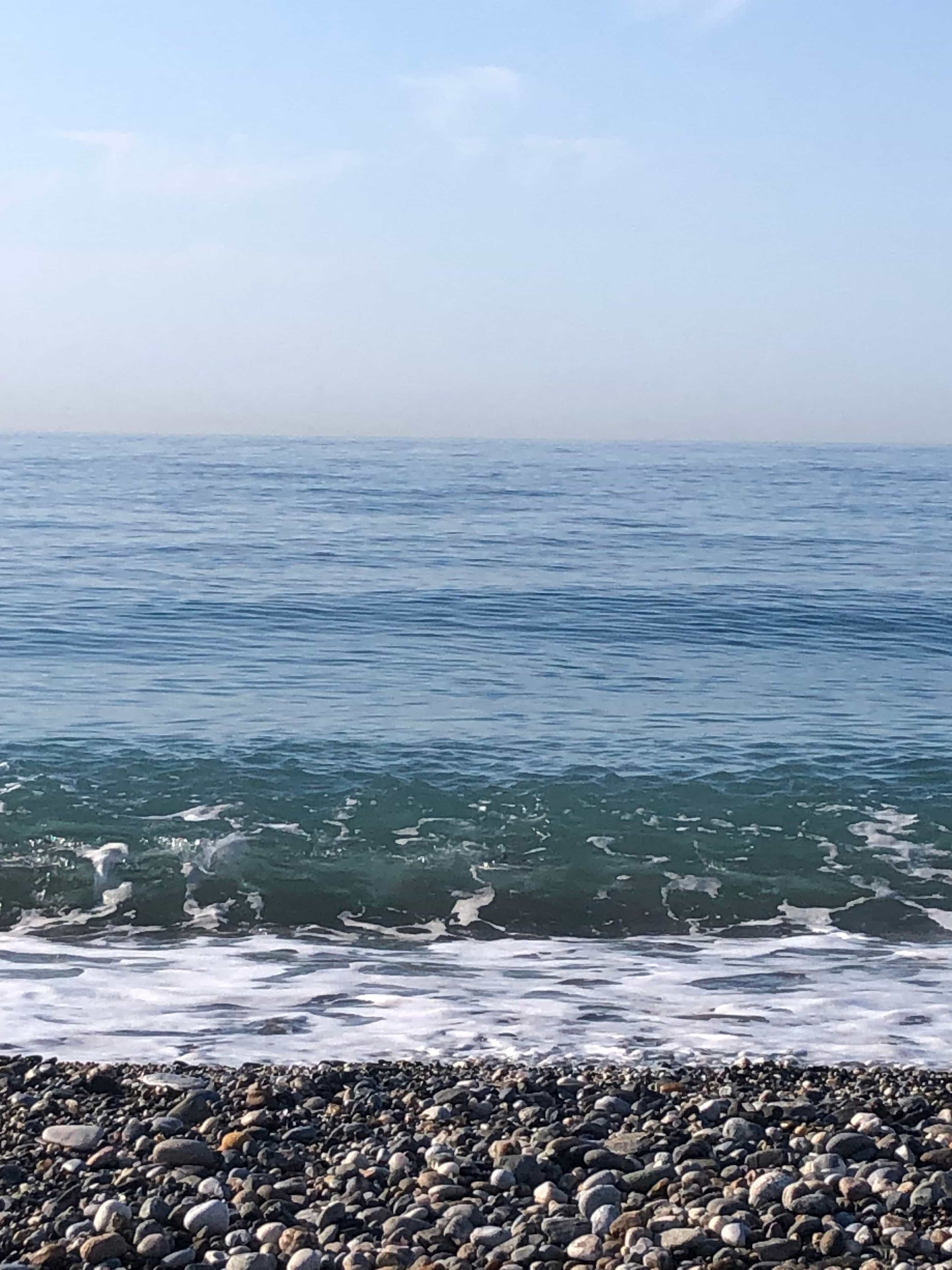 Fotografía de la orilla del mar con piedras y olas pequeñas