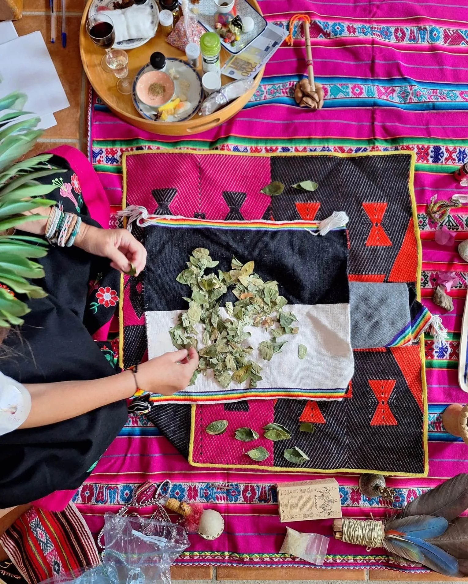 Vista desde arriba de Carmen Sánchez realizando un Despacho Andino sobre Missa Andina. Se ven los diferentes ingredientes y herramientas que se usan en el altar.