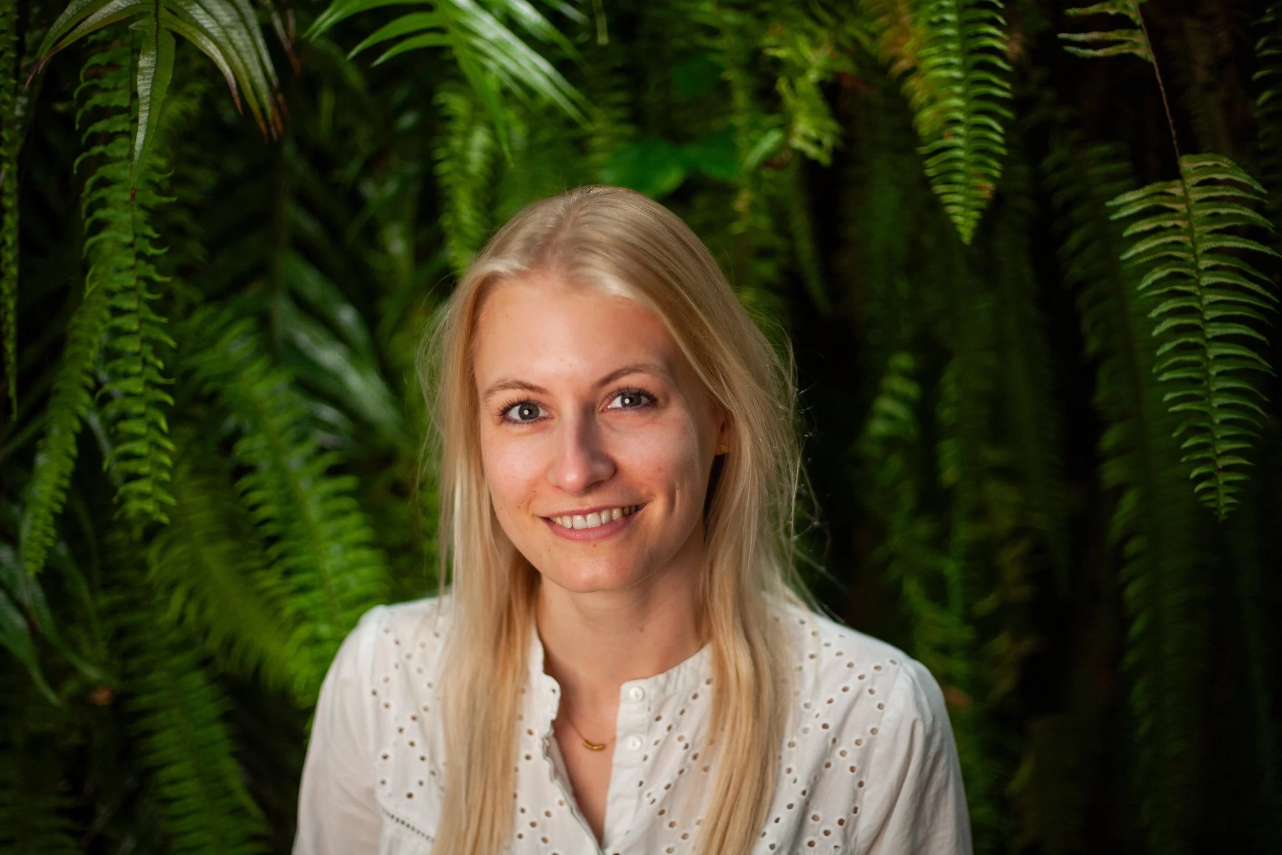 Profielfoto van een blonde vrouw voor een groene achtergrond.
