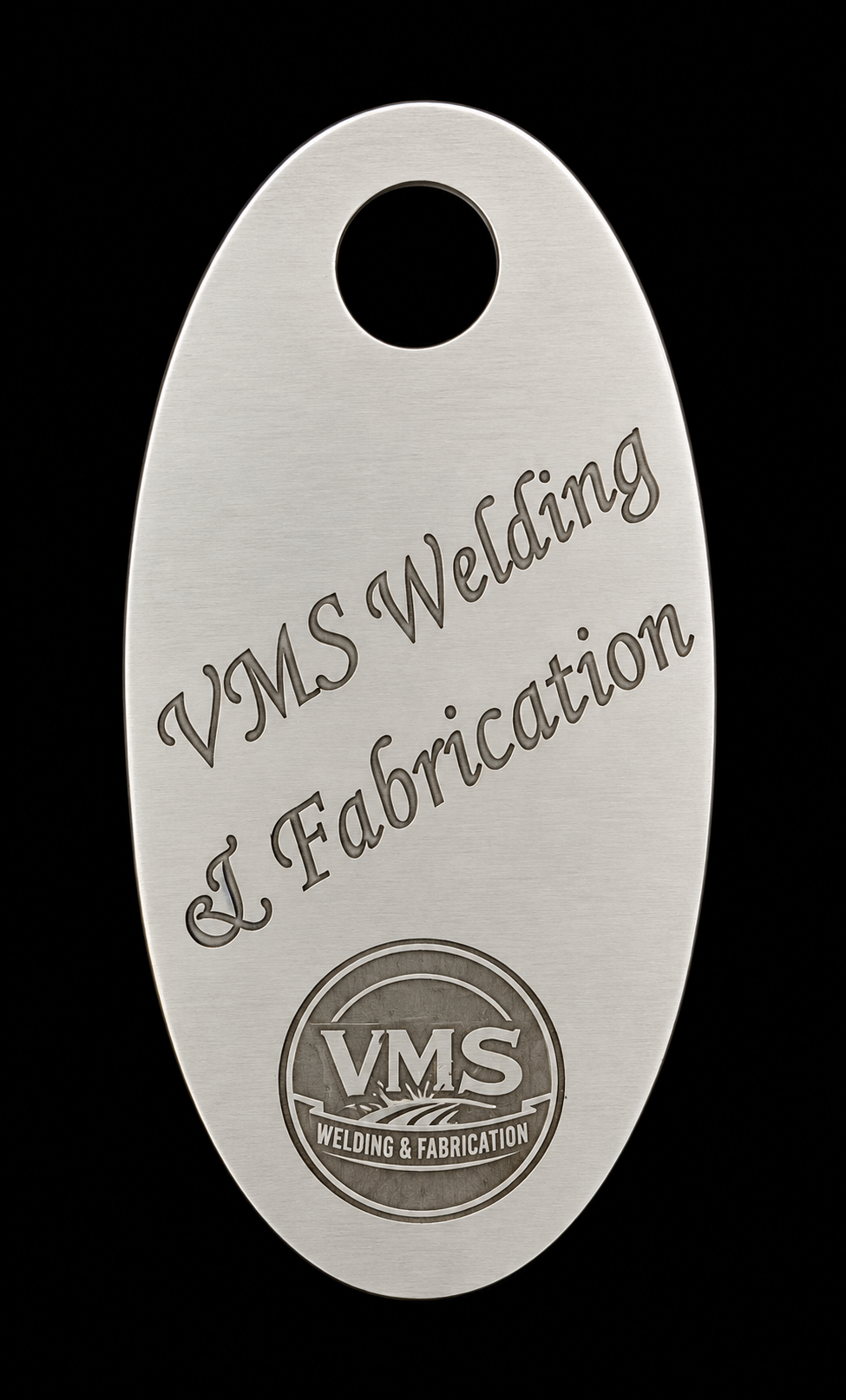 Metal tag engraved with "VMS Welding & Fabrication" and logo, on a black background.