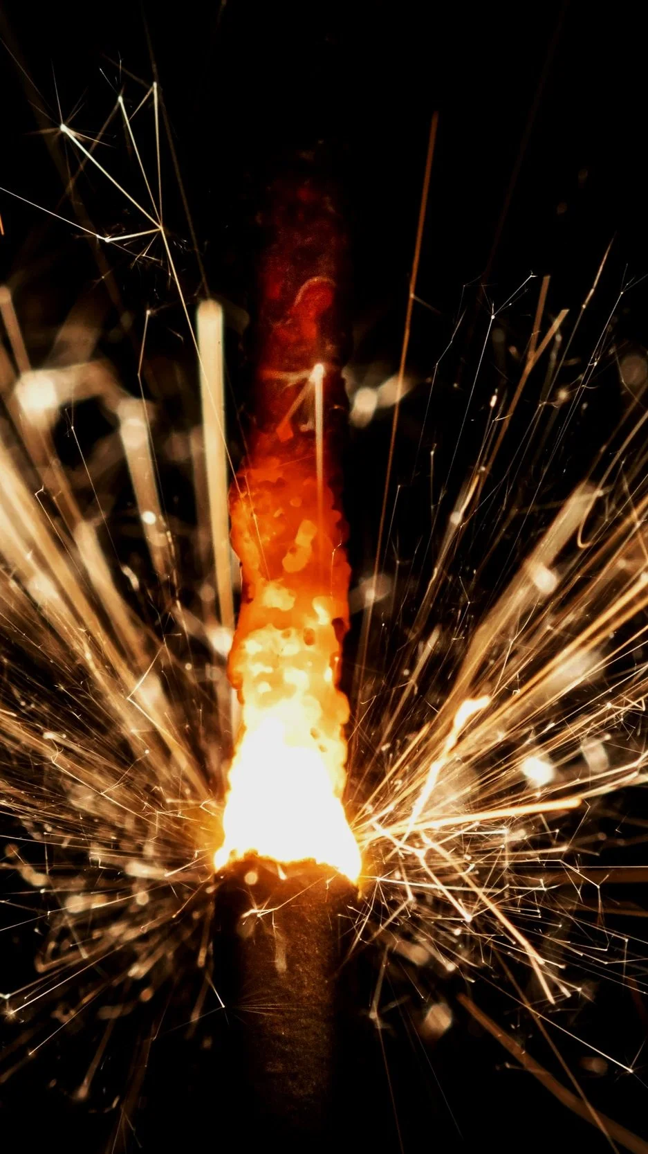 A sparkler burning with bright sparks and sparks flying outward.