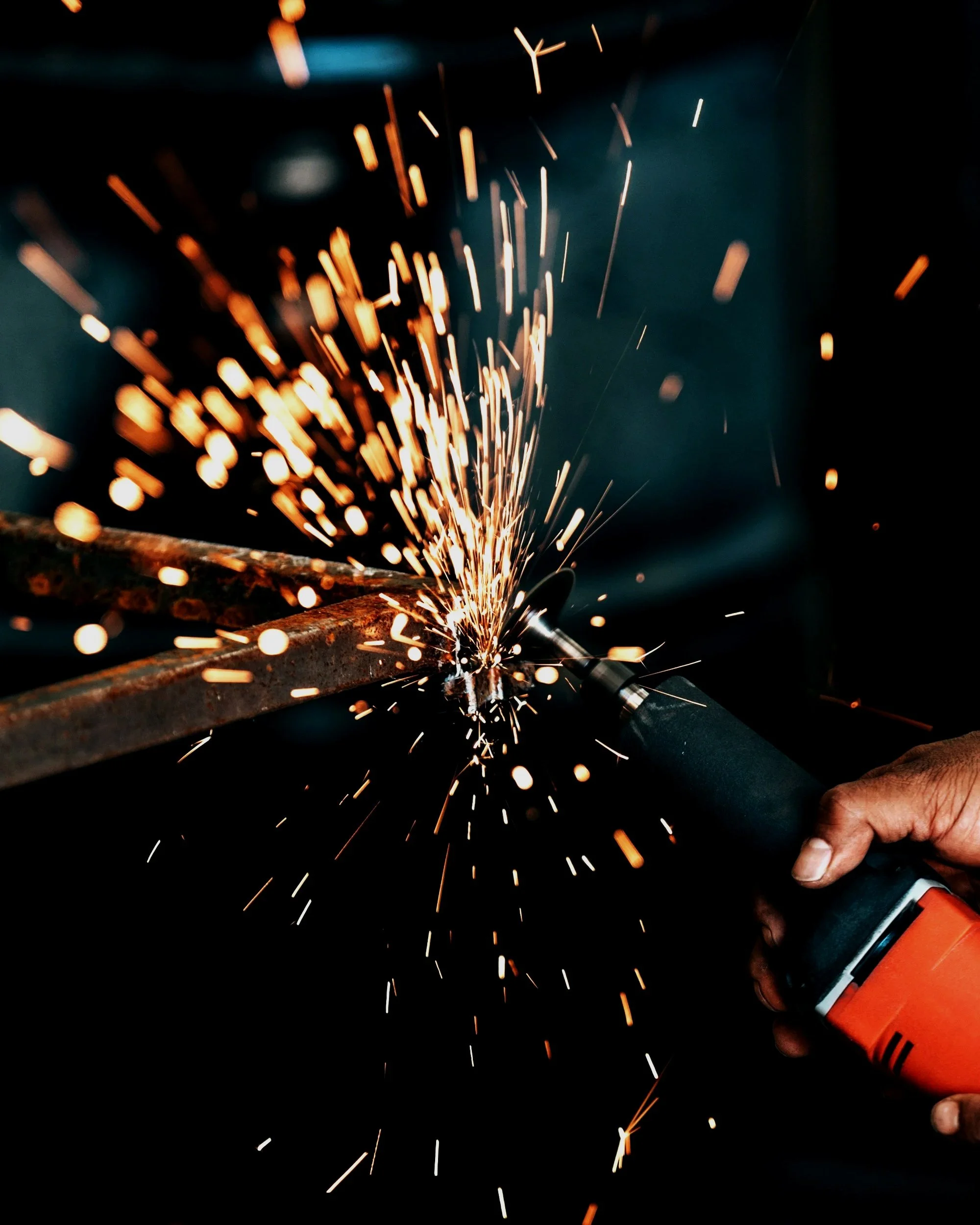 Person using an angle grinder to cut metal, with sparks flying all around.