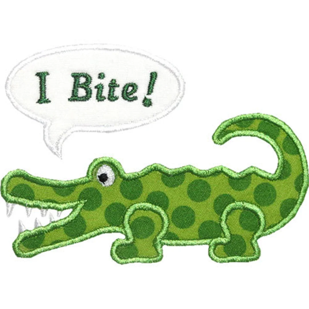 A cute embroidered patch of a cartoon green crocodile with dark green spots, a friendly eye, and a wide toothy grin, with a speech bubble saying "I Bite!"