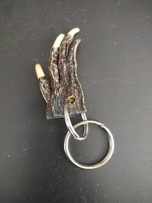 A keychain with a metal spring and a piece of curling fur or feathers attached to it, resembling a claw or paw.