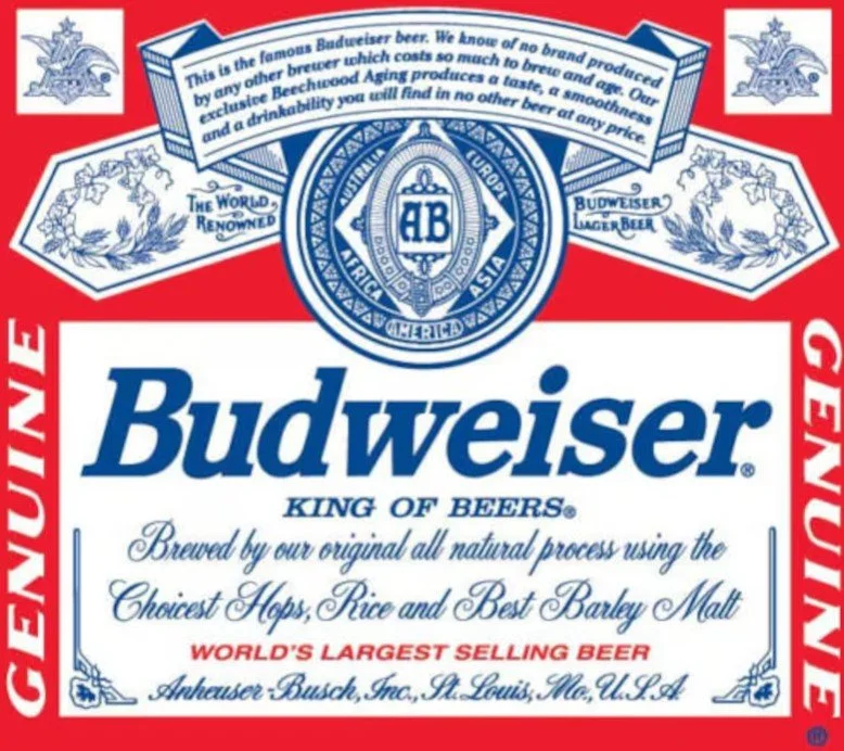 Budweiser beer label featuring the brand name in bold blue letters, the slogan 'King of Beers,' and information about the beer's natural process, ingredients, and origin, decorated with logos and text in red, white, and blue.